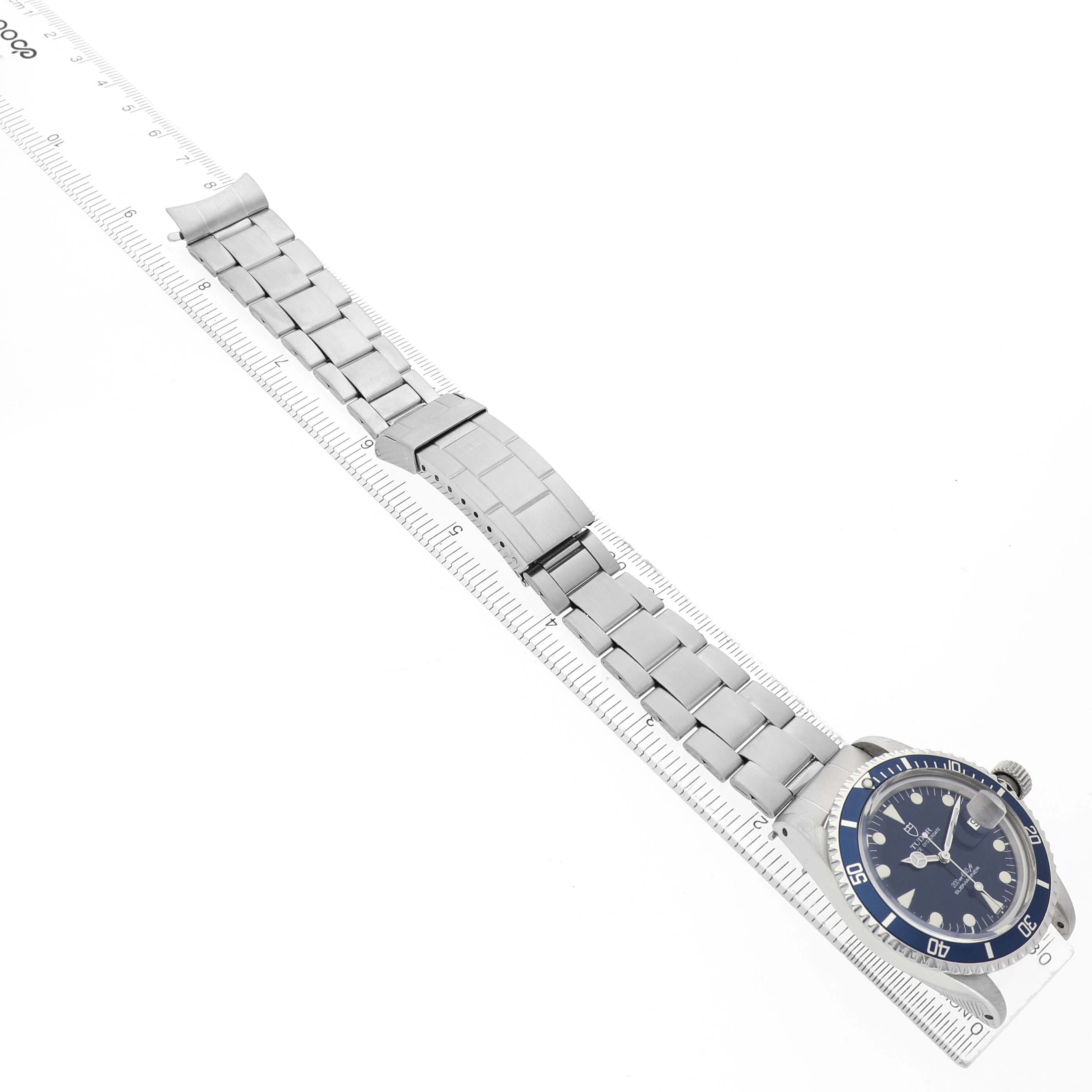 The Tudor Prince 76100 Men's Stainless Steel Blue Dial watch is shown at an angle displaying the face, bracelet, and clasp alongside a ruler for size reference.