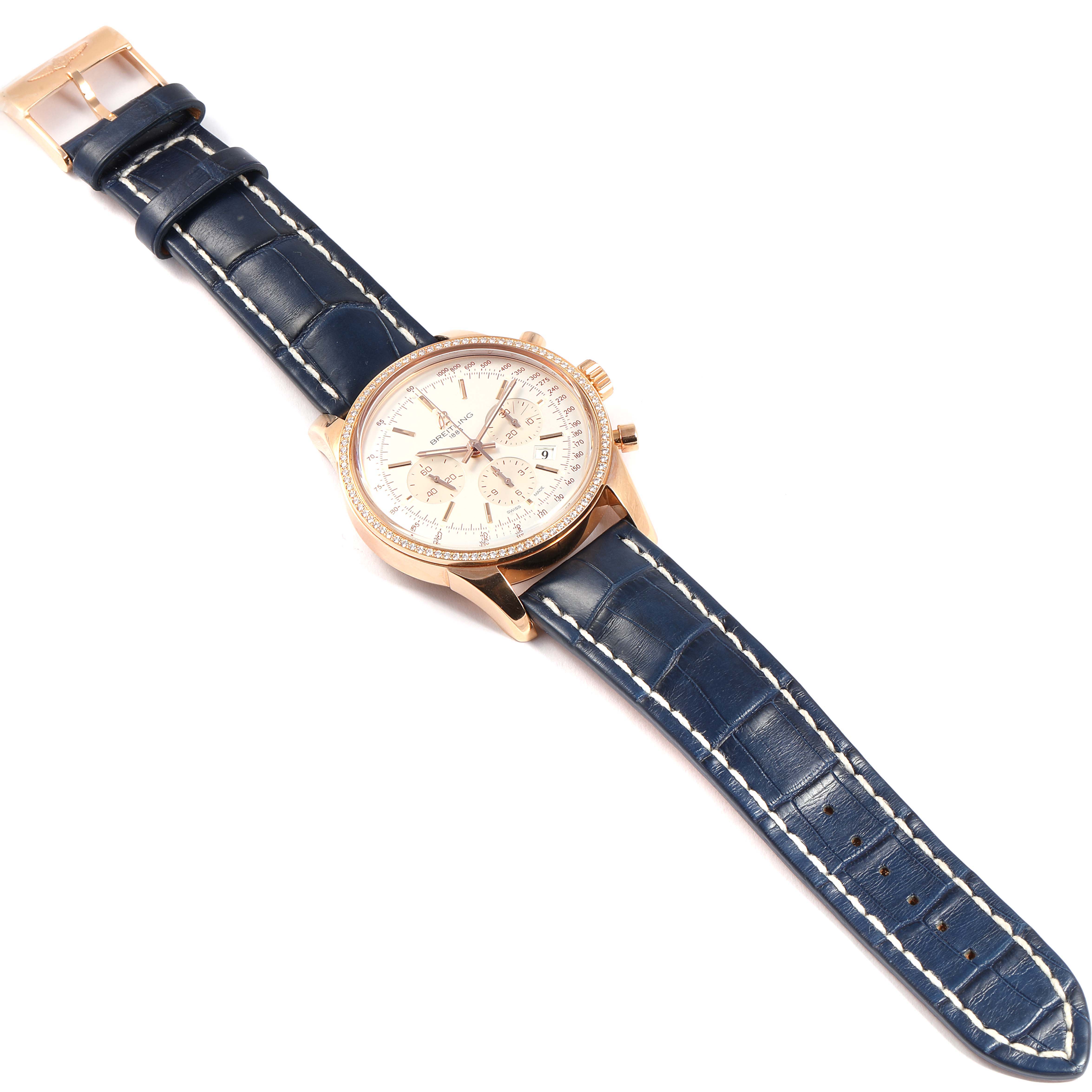 The image shows the Breitling Transocean RB0152 Men's Rose Gold Silver Dial RB0152 Men's Rose Gold Silver Dial watch positioned flat with a focus on the dial and blue leather strap.