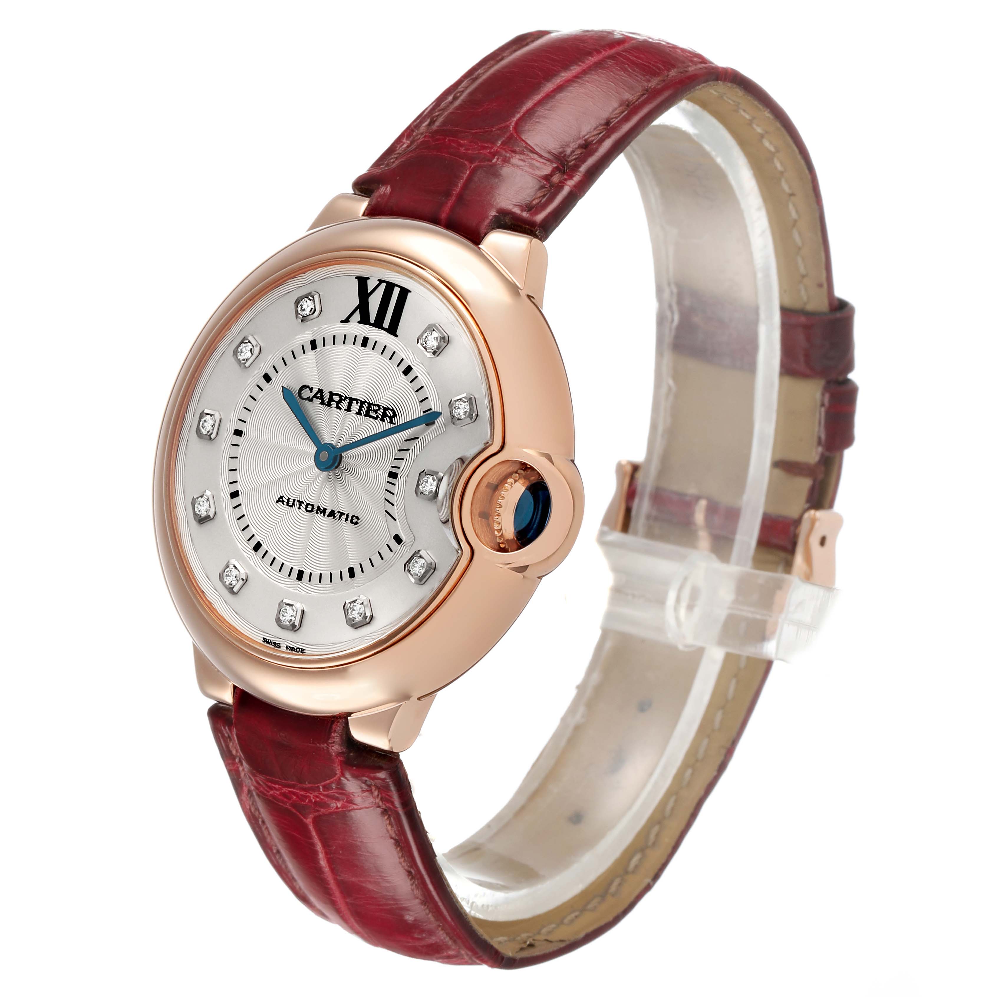The Cartier Ballon Bleu WJBB0010 Women's Rose Gold Silver Dial watch is shown at an angle highlighting its dial, crown, and red leather strap.