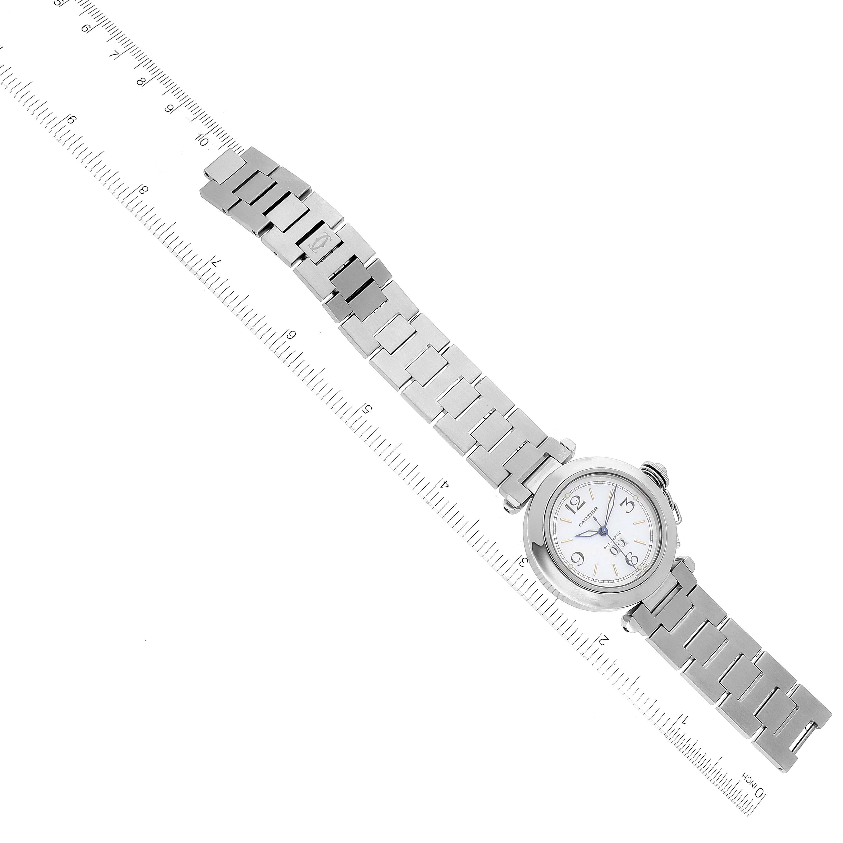 The Cartier Pasha W31044M7 Men's Stainless Steel White Dial W31044M7 Men's Stainless Steel White Dial watch is displayed fully extended with its stainless steel bracelet and round face, alongside a ruler for scale.
