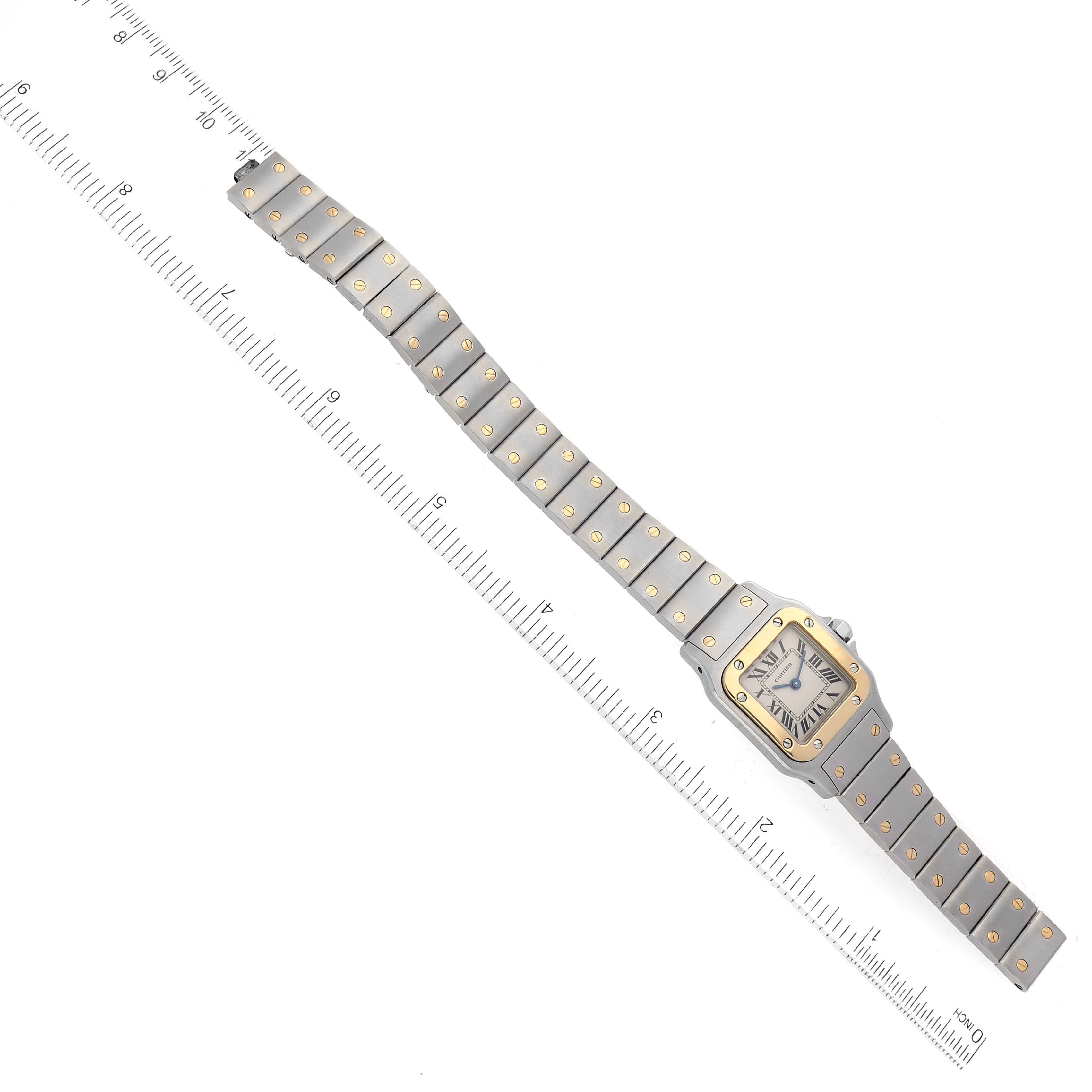 The image shows a top view of a Cartier Santos W20012C4 Women's Steel and Gold (two tone) Silver Dial W20012C4 Women's Steel and Gold (two tone) Silver Dial watch with its full bracelet extended alongside a ruler for size reference.