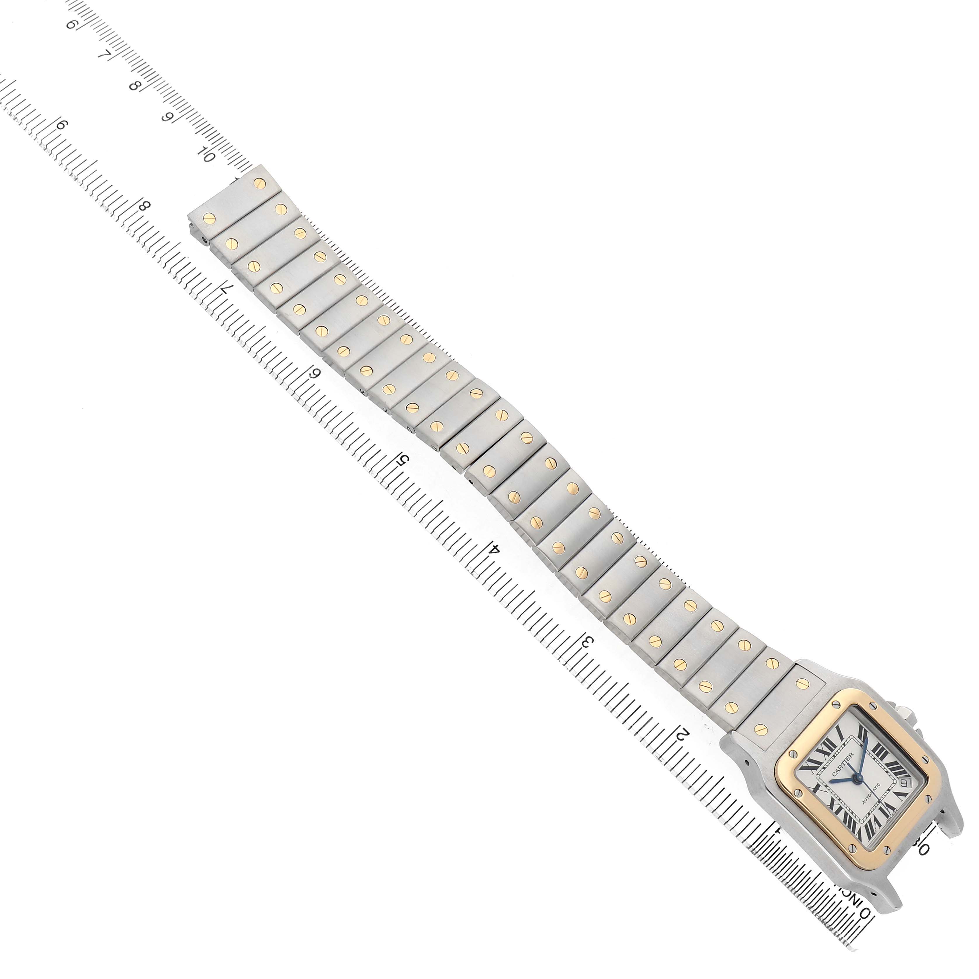 The Cartier Santos W20099C4 Men's Stainless Steel Silver Dial watch is shown at an angle highlighting the face, bracelet, and clasps with a ruler for scale.
