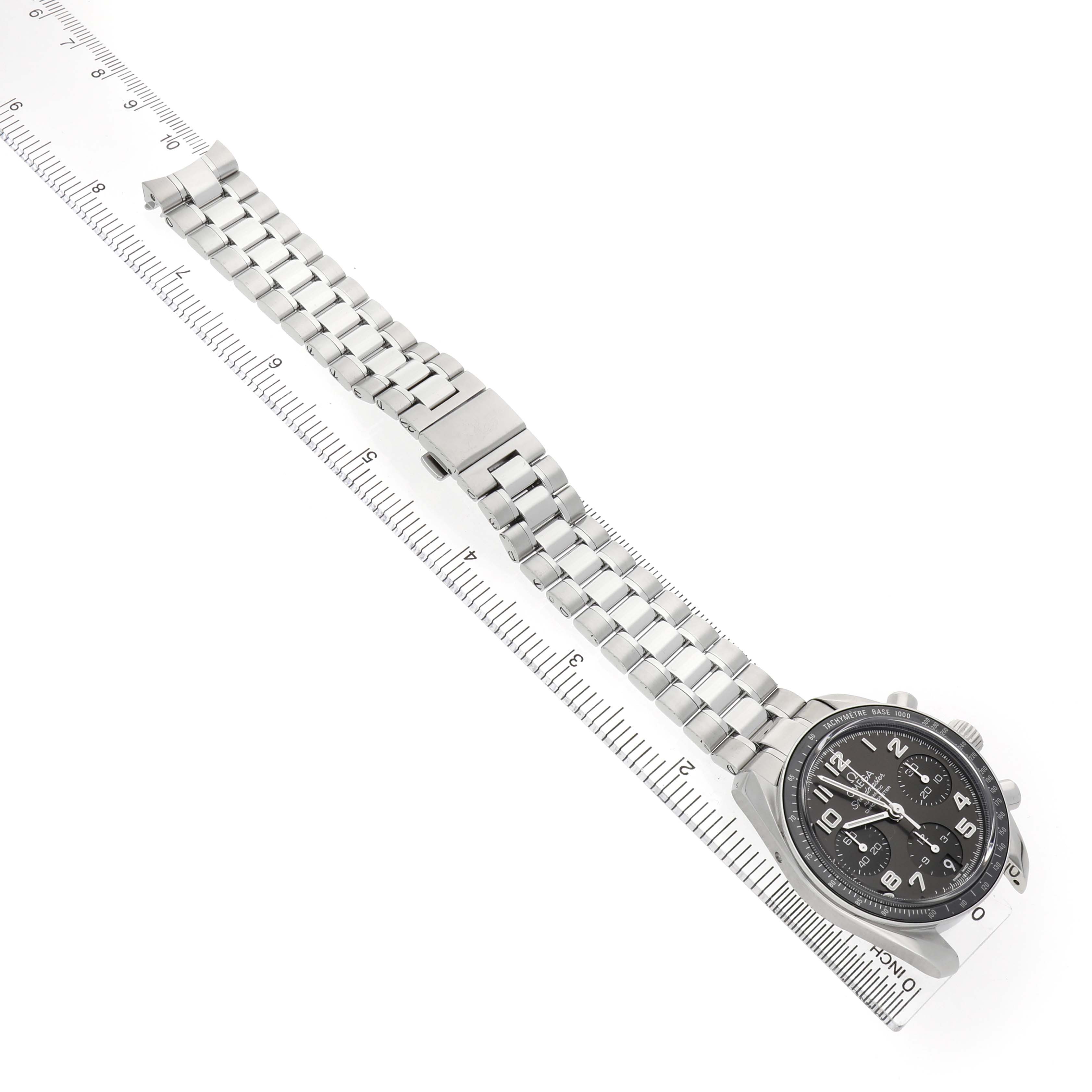 The Omega Speedmaster 324.30.38.40.06.001 Men's Stainless Steel Grey Dial watch is shown at an angle, displaying the face and stainless steel bracelet alongside a ruler.