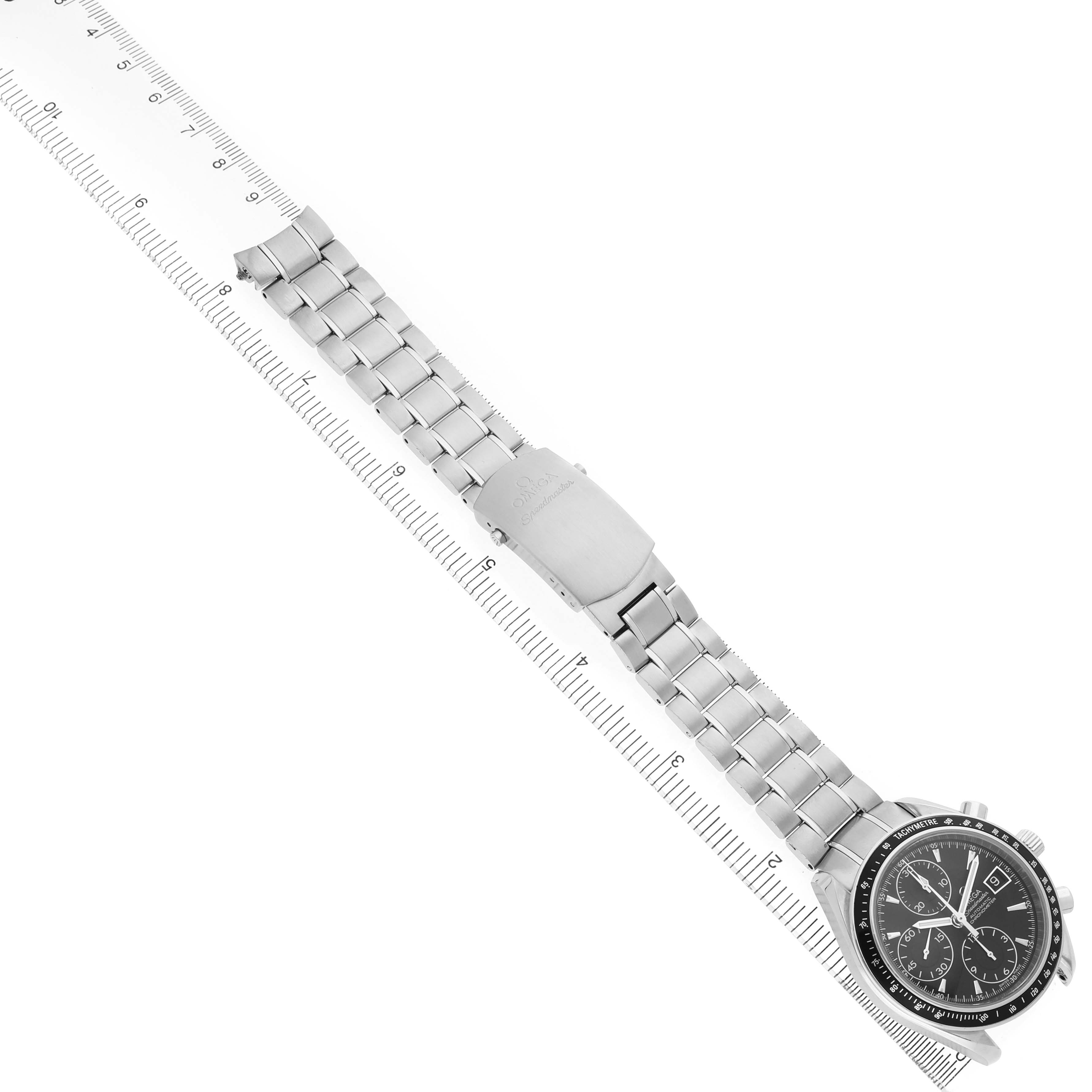 The Omega Speedmaster 3210.50.00 Men's Stainless Steel Black Dial watch is shown diagonally, highlighting its face and stainless steel bracelet beside a ruler for scale.