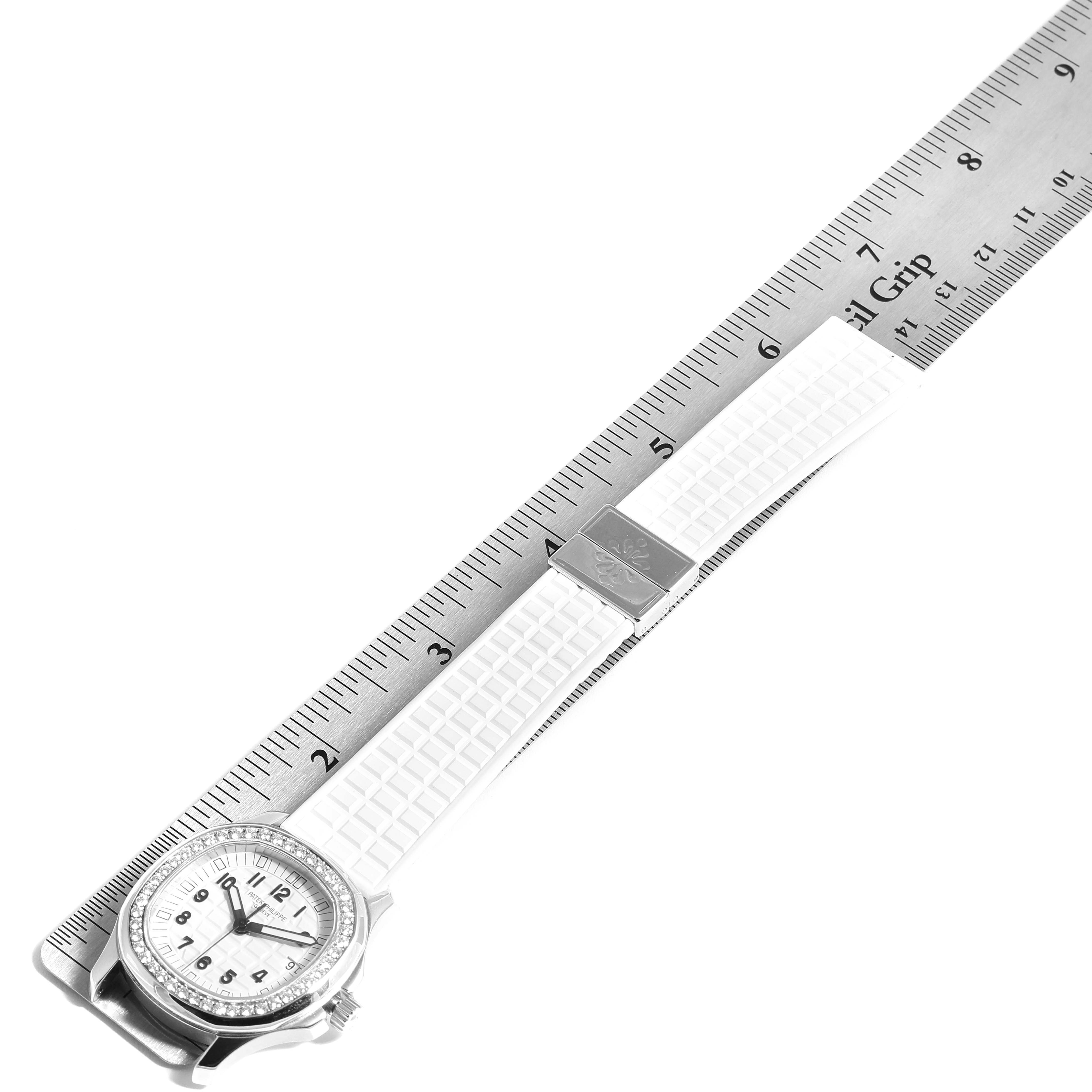 The image shows a Patek Philippe Aquanaut 5067 Women's Stainless Steel White Dial 5067 Women's Stainless Steel White Dial watch laid flat next to a ruler, showcasing its face, bezel, and white strap.