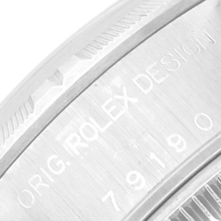 This close-up image shows the side of a Rolex Date 79190 Women
s Stainless Steel Silver Dial 79190 Women
s Stainless Steel Silver Dial model, focusing on the engraved writing and bezel.