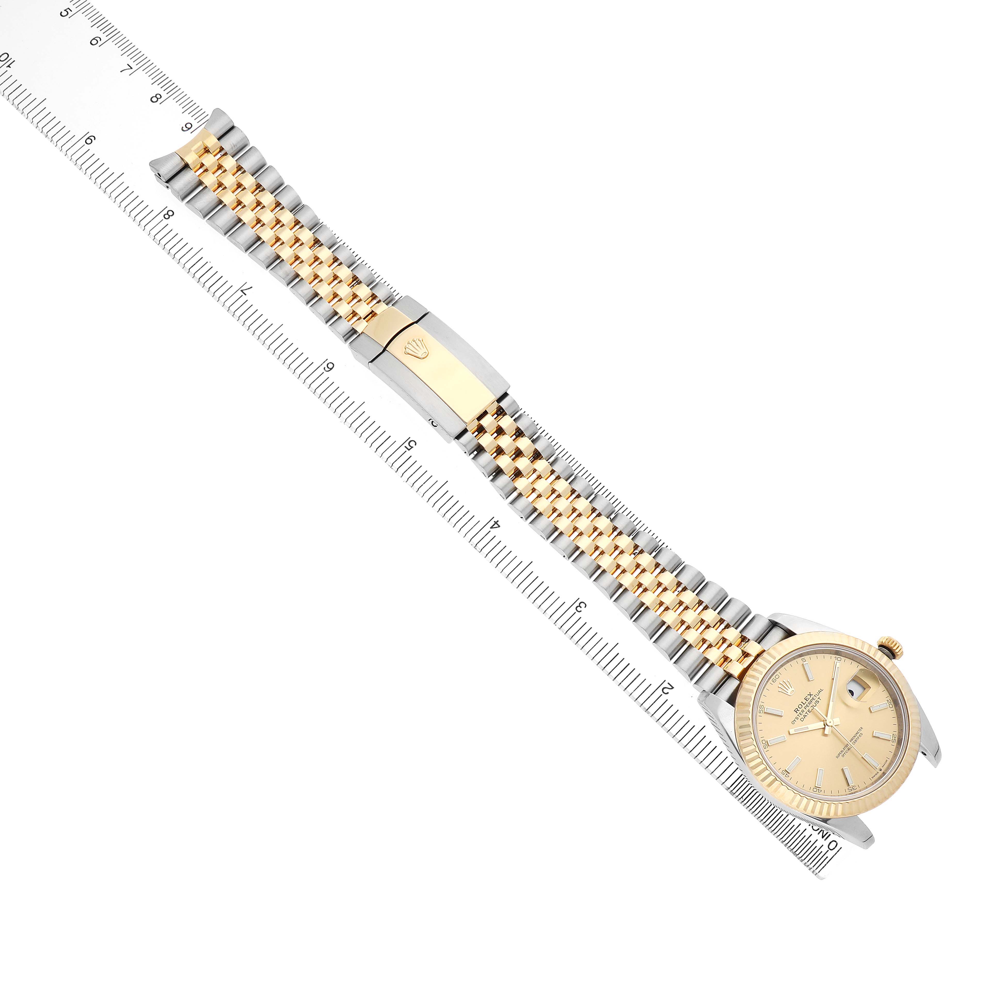 The Rolex Datejust 41 126333 Men's Steel and Gold (two tone) Champagne Dial is shown from an overhead angle, displaying its face, bracelet, and clasp alongside a ruler for scale.