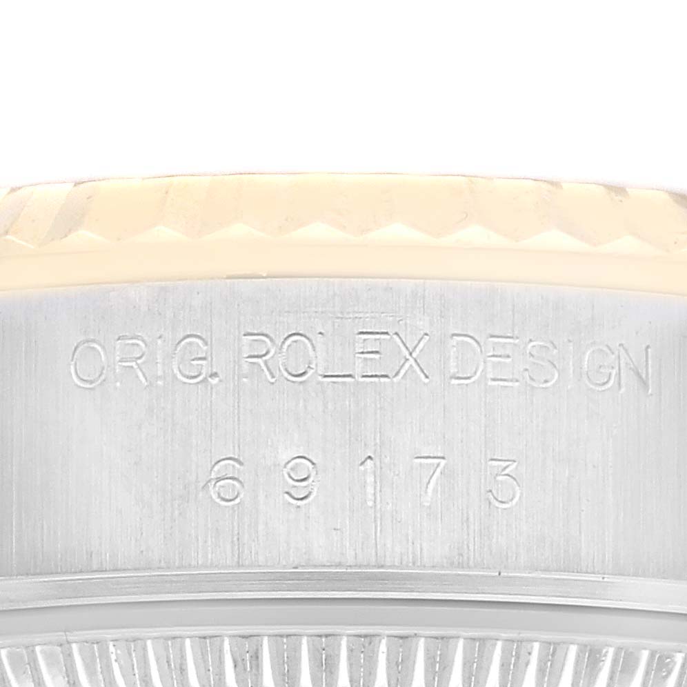 The image shows a close-up of the side of a Rolex Datejust 69173 Women's Steel and Gold (two tone) Champagne Dial 69173 Women's Steel and Gold (two tone) Champagne Dial watch case, featuring engraving with the serial number "69173" and "ORIG. ROLEX DESIGN."