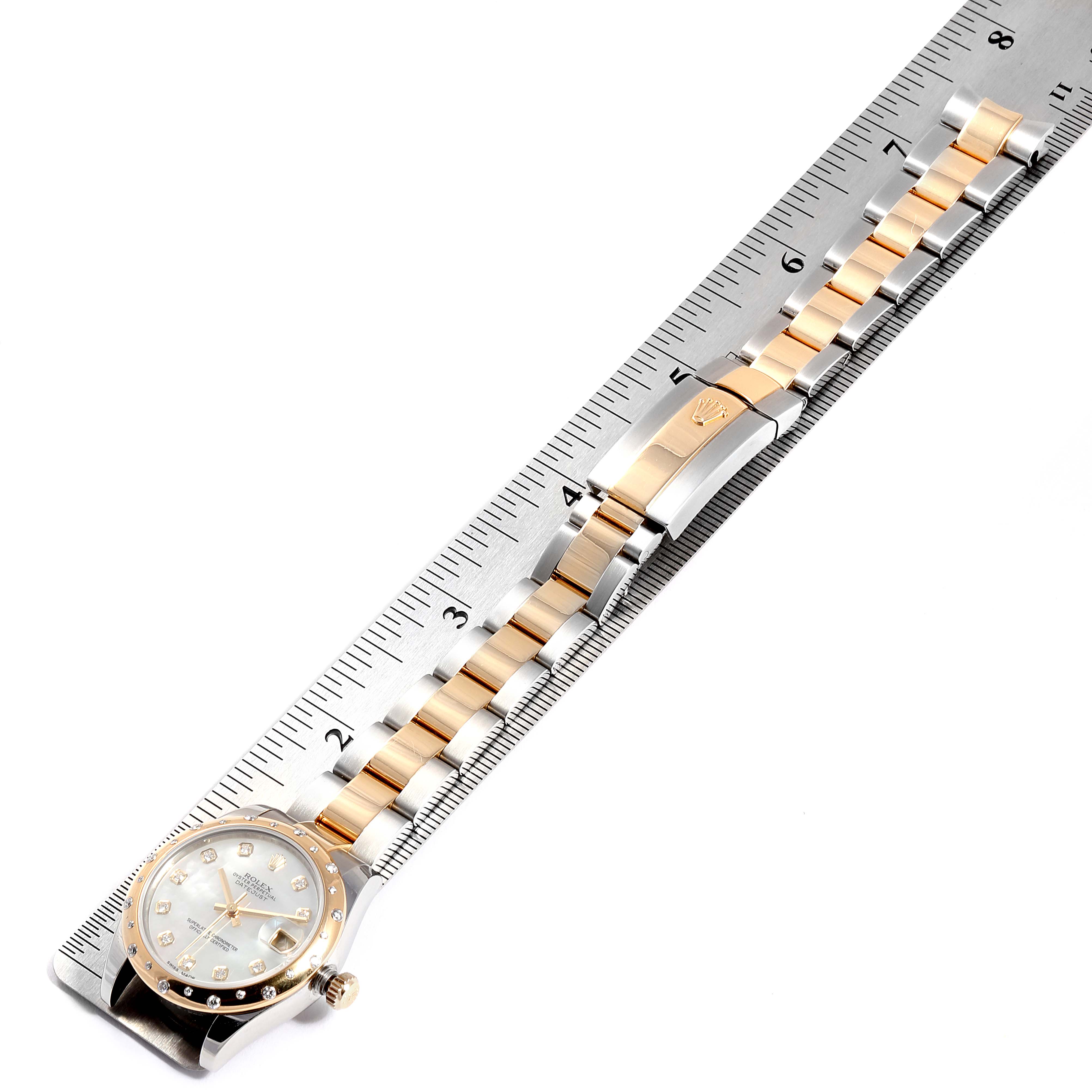 The image shows a Rolex Mid-Size 178343 Women's Steel and Gold (two tone) Mother of Pearl Dial 178343 Women's Steel and Gold (two tone) Mother of Pearl Dial watch laid flat against a ruler, displaying its bracelet and face.