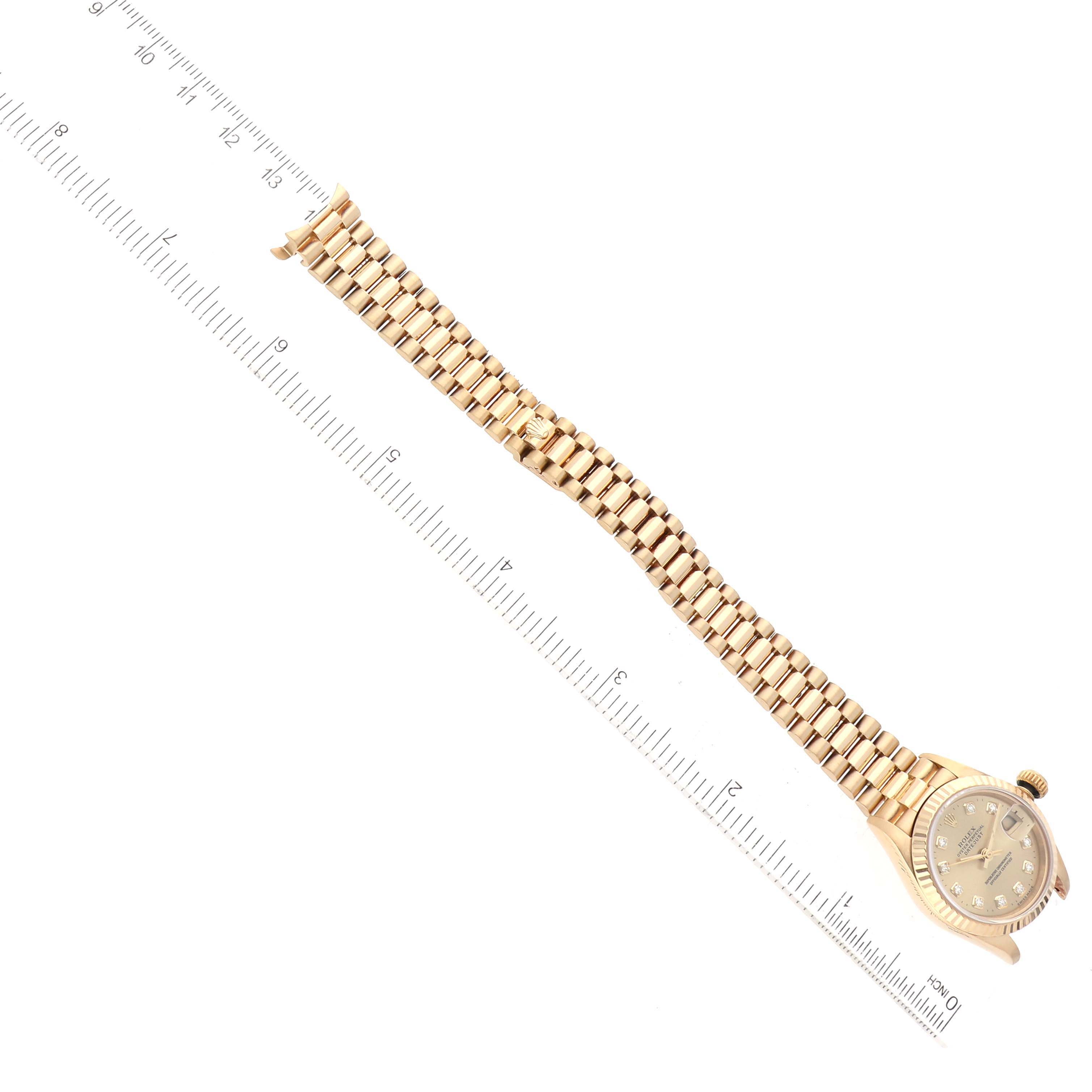 The image shows a side view of a Rolex President 69178 Women's Yellow Gold Beige Dial 69178 Women's Yellow Gold Beige Dial model watch with its full band extended and positioned along a ruler.