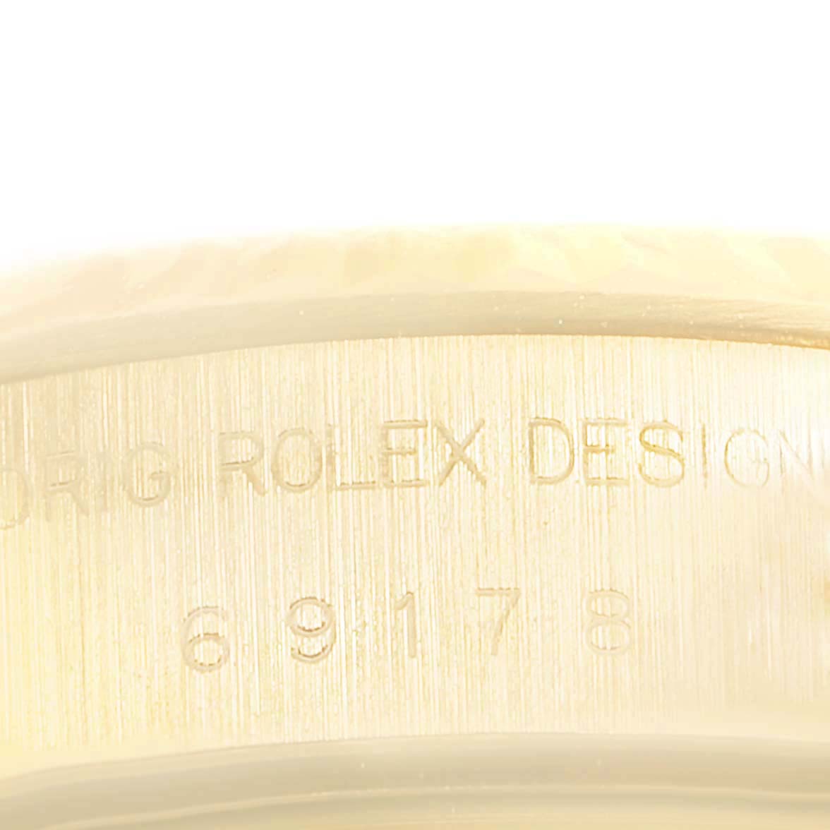 This image shows a close-up of the side casing on a Rolex President 69178 Women's Yellow Gold Beige Dial 69178 Women's Yellow Gold Beige Dial model with the "ORIG ROLEX DESIGN" and serial number engraving.