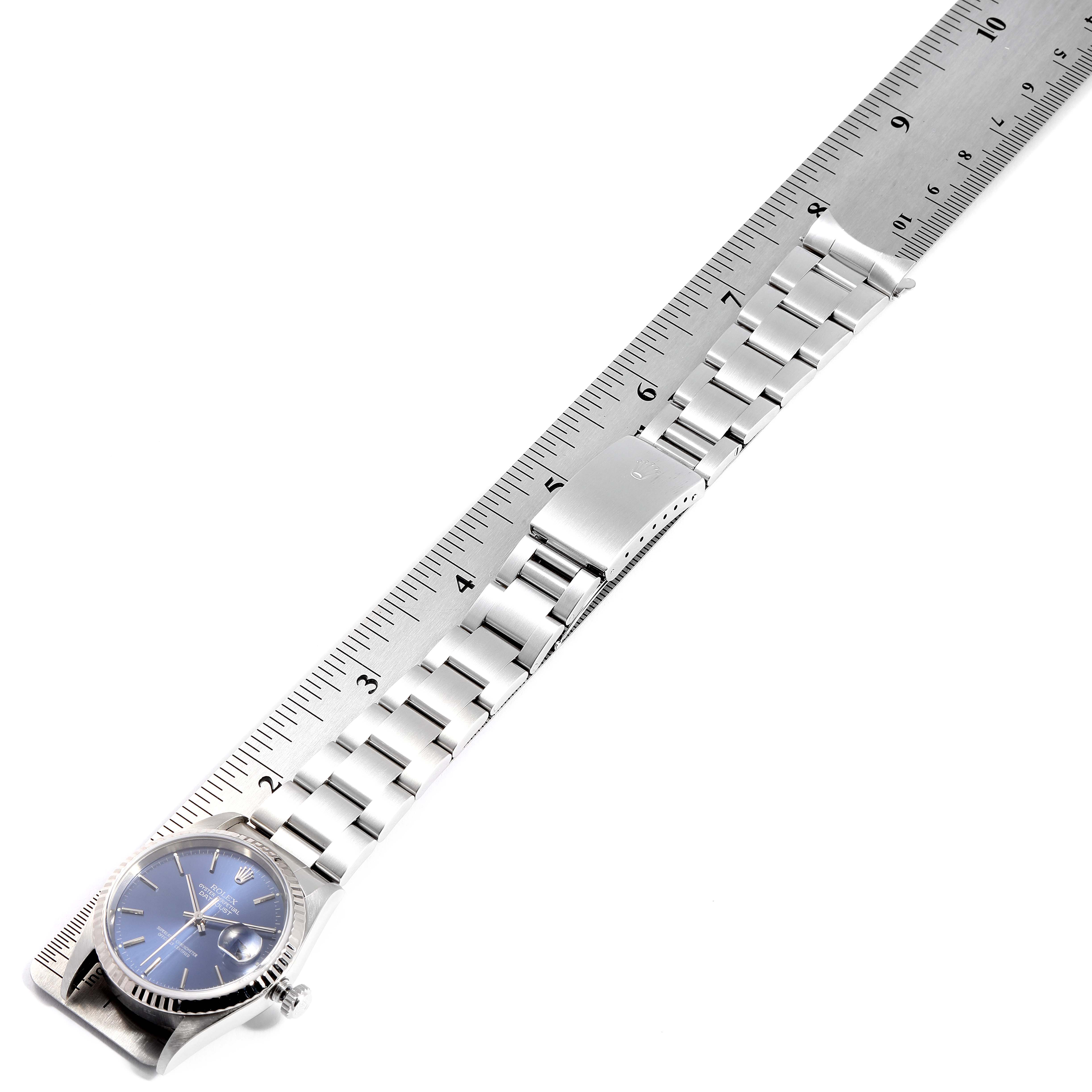 The image shows a Rolex Datejust 16234 Men
s Stainless Steel Blue Dial 16234 Men
s Stainless Steel Blue Dial watch laid flat alongside a ruler, highlighting the strap and clasp.