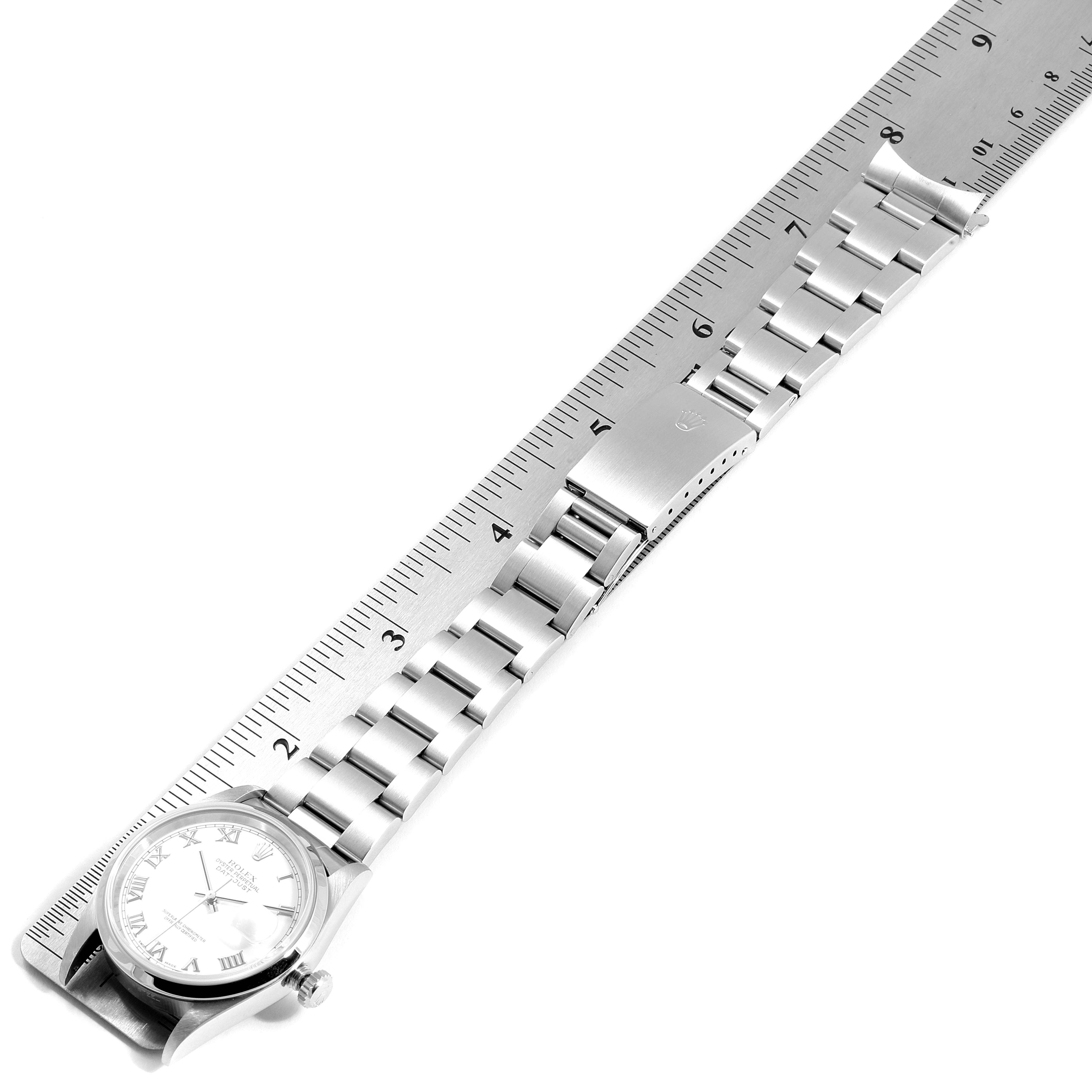 The Rolex Datejust 16200 Men's Stainless Steel White Dial 16200 Men's Stainless Steel White Dial watch is shown from a top-down angle, alongside a metal ruler, displaying its face, band, and clasp.