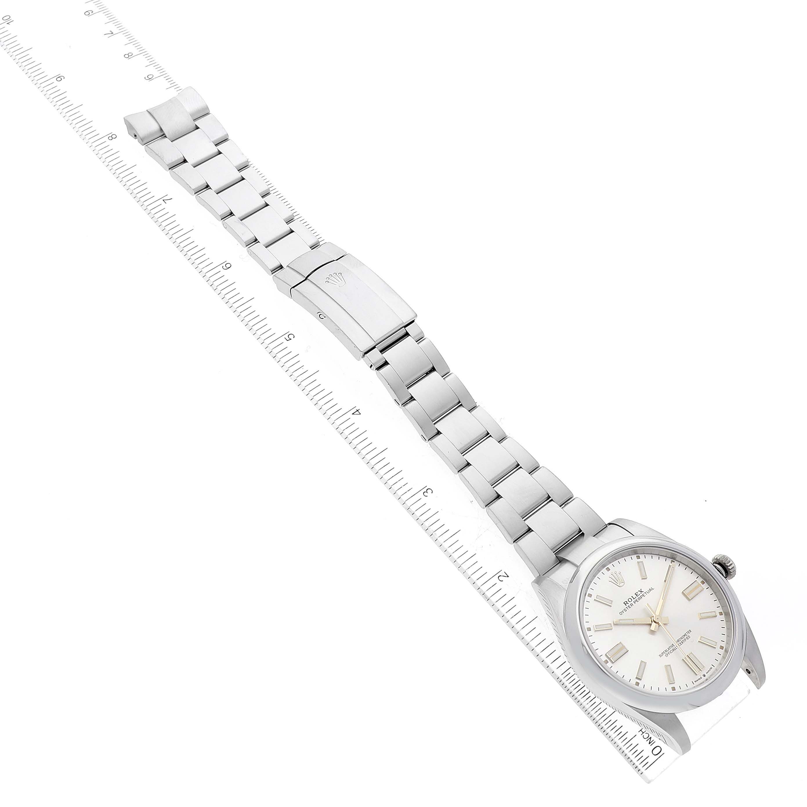 The image shows a full view of the Rolex Oyster Perpetual 124300 Men
s Stainless Steel Silver Dial 124300 Men
s Stainless Steel Silver Dial watch, including the bracelet and clasp, next to a ruler for scale.