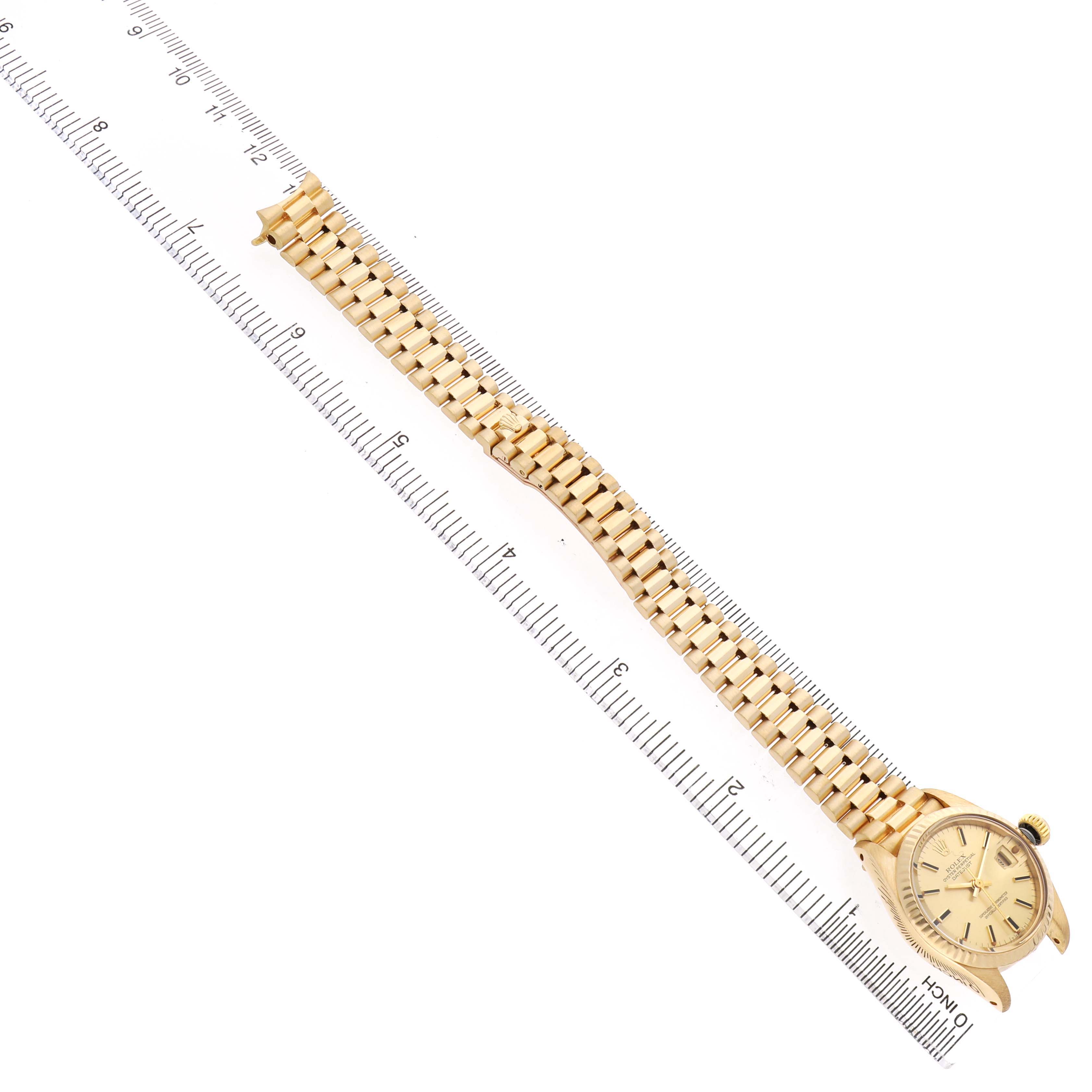 The Rolex President 6917 Women's Yellow Gold Champagne Dial watch is shown from a top-down angle, featuring its dial, case, and full bracelet stretched over a ruler.