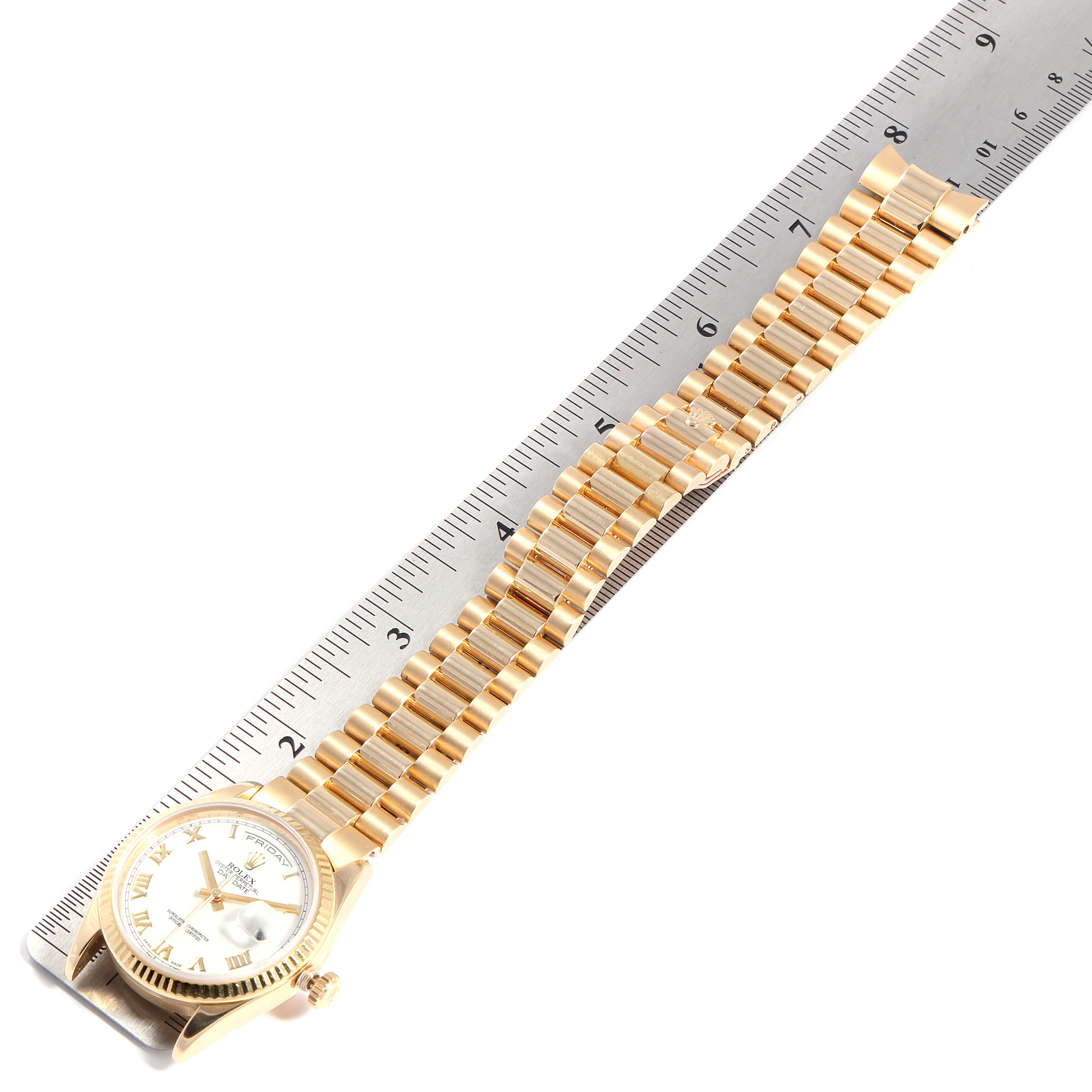The image shows a Rolex President 118238 Men
s Yellow Gold White Dial 118238 Men
s Yellow Gold White Dial model watch laid flat, with the face and full gold bracelet visible, next to a ruler for scale.