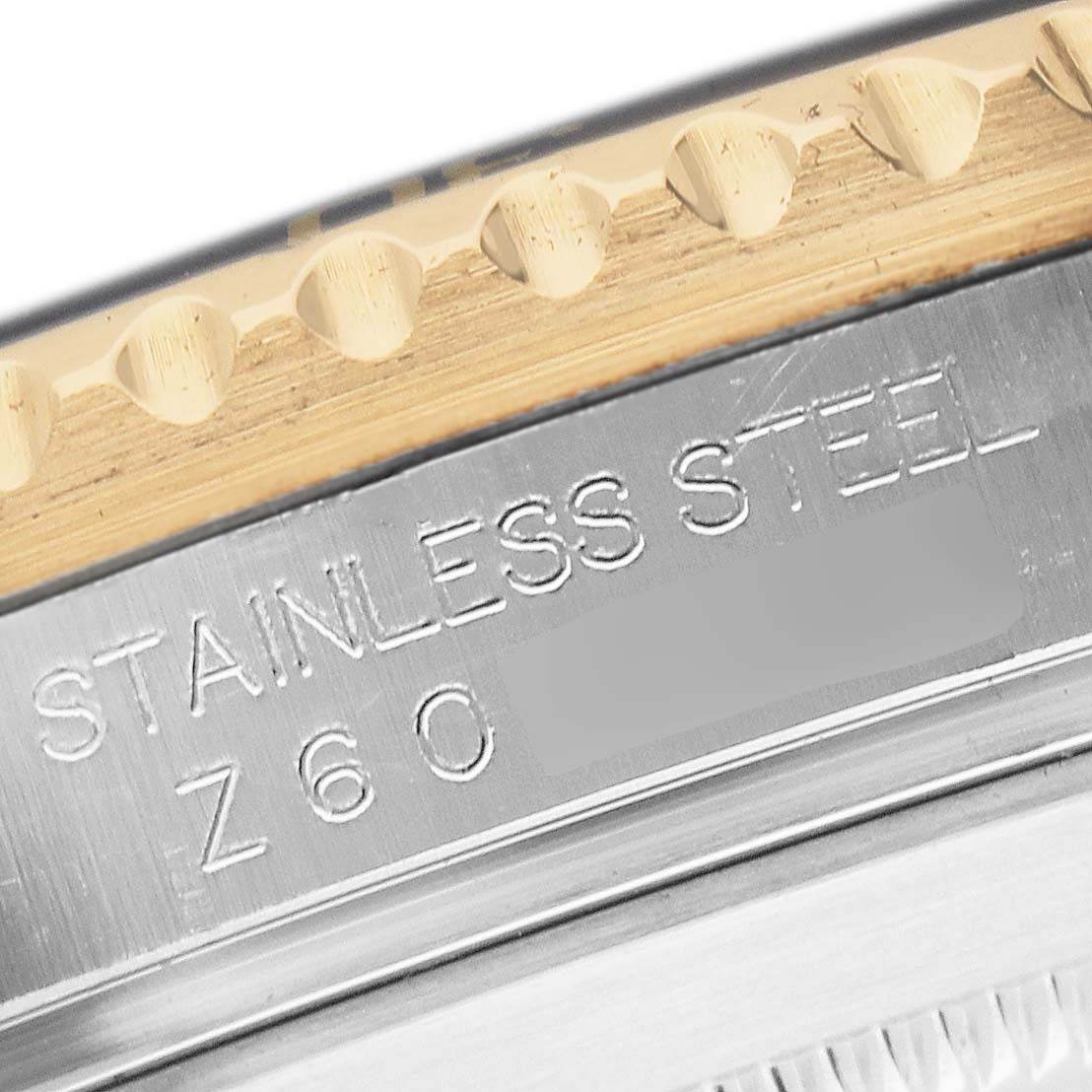 The image shows a close-up of the Rolex Submariner 16613 T Men's Steel and Gold (two tone) Blue Dial's side, highlighting "STAINLESS STEEL" engraving on the case.