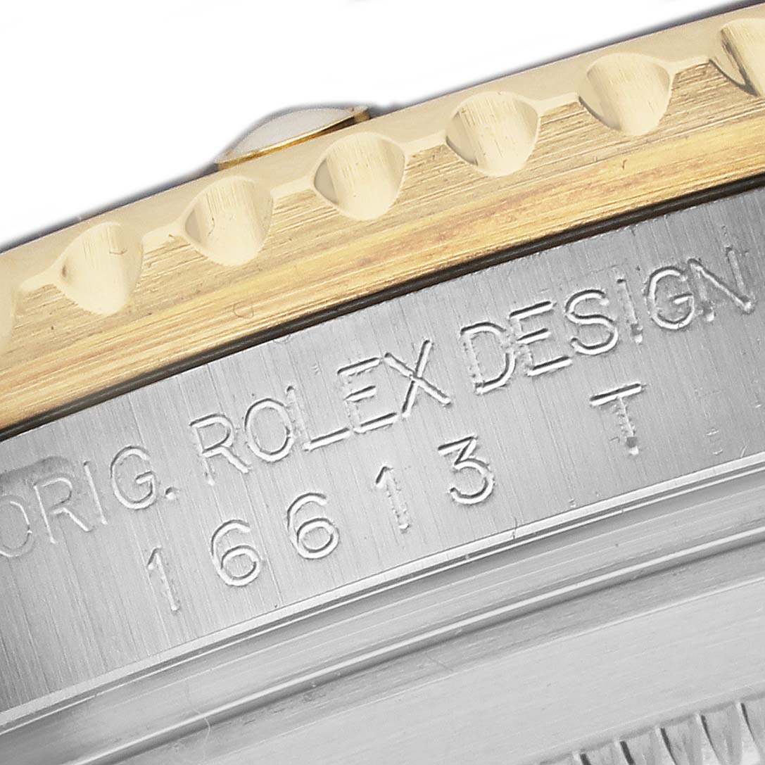 The image shows a close-up of the bezel and engravings on the side of a Rolex Submariner 16613 T Men's Steel and Gold (two tone) Blue Dial watch.