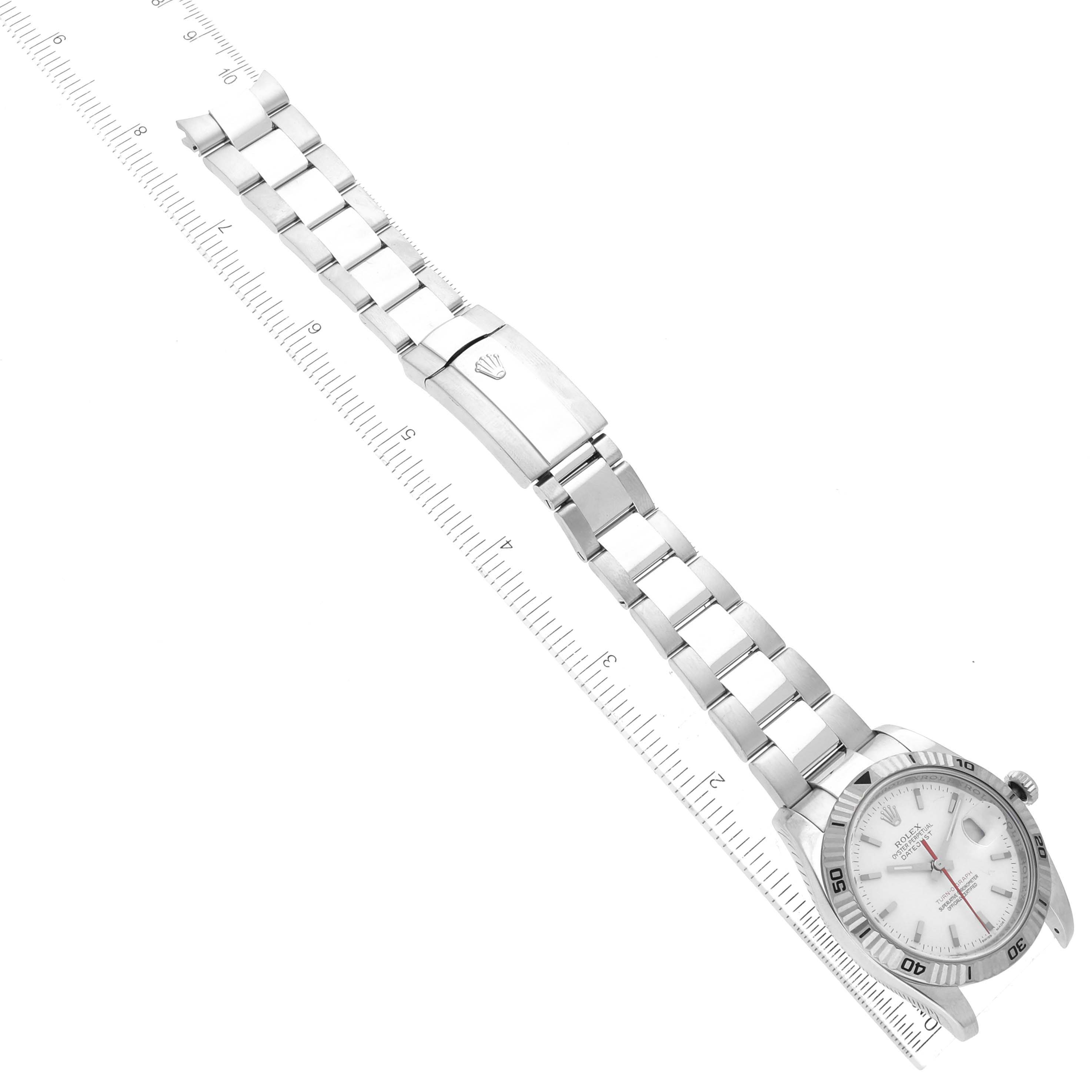 The Rolex Turn-o-Graph 116264 Men's Stainless Steel White Dial 116264 Men's Stainless Steel White Dial watch is shown at an overhead angle, displaying the face, bracelet, and clasp on a ruler.