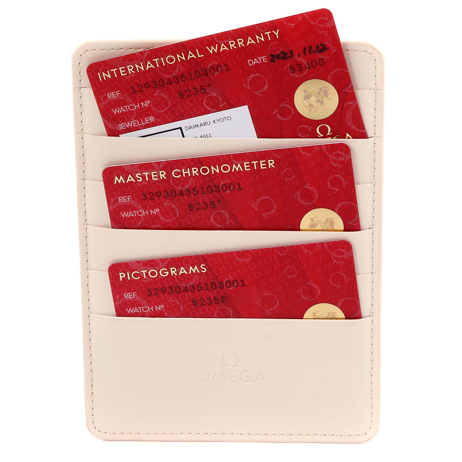 This image shows a beige Omega cardholder containing three red cards labeled International Warranty, Master Chronometer, and Pictograms.