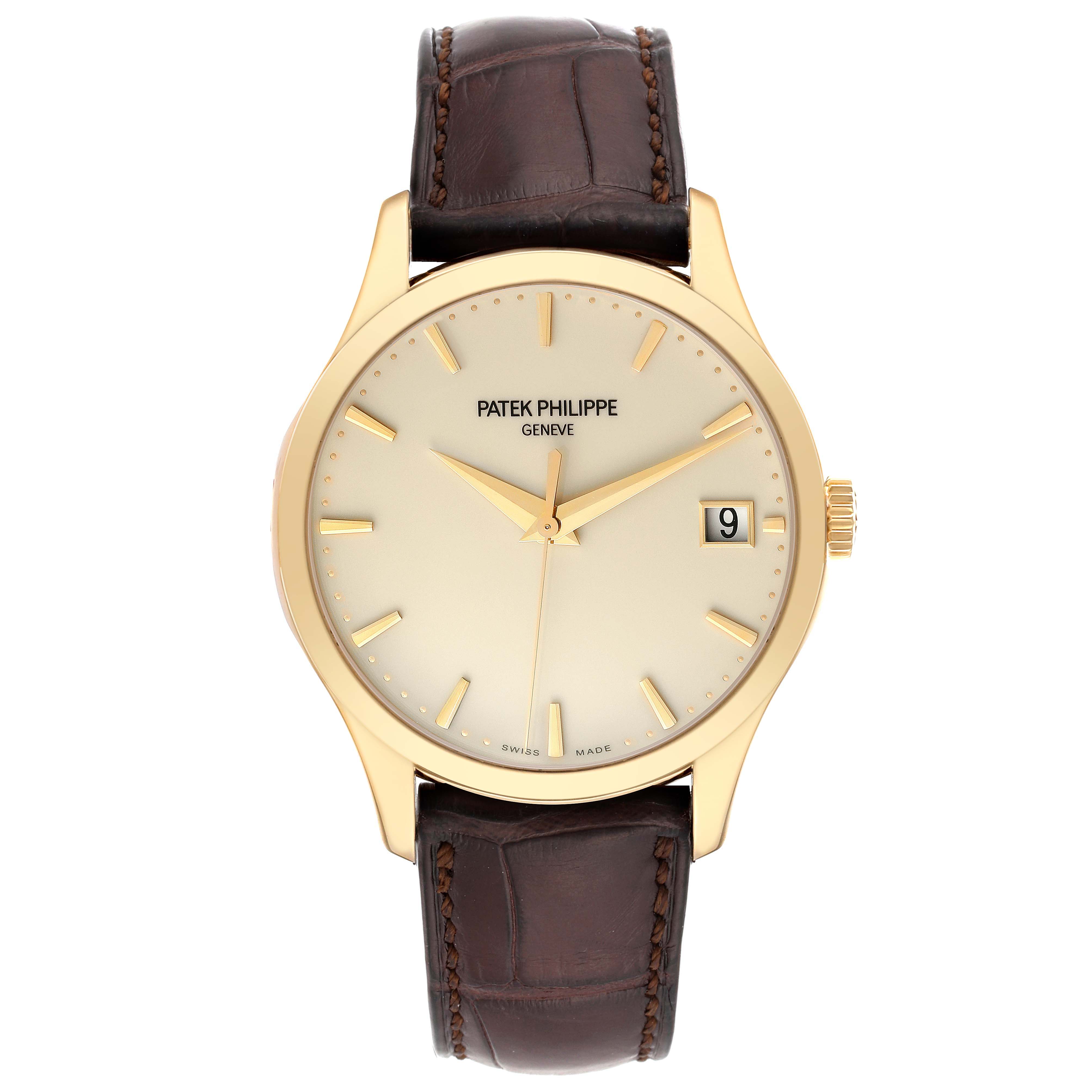 The image shows a front view of the Patek Philippe Calatrava 5227J-001 Men's Yellow Gold Beige Dial 5227J-001 Men's Yellow Gold Beige Dial watch, highlighting the dial, hands, date window, and brown leather strap.