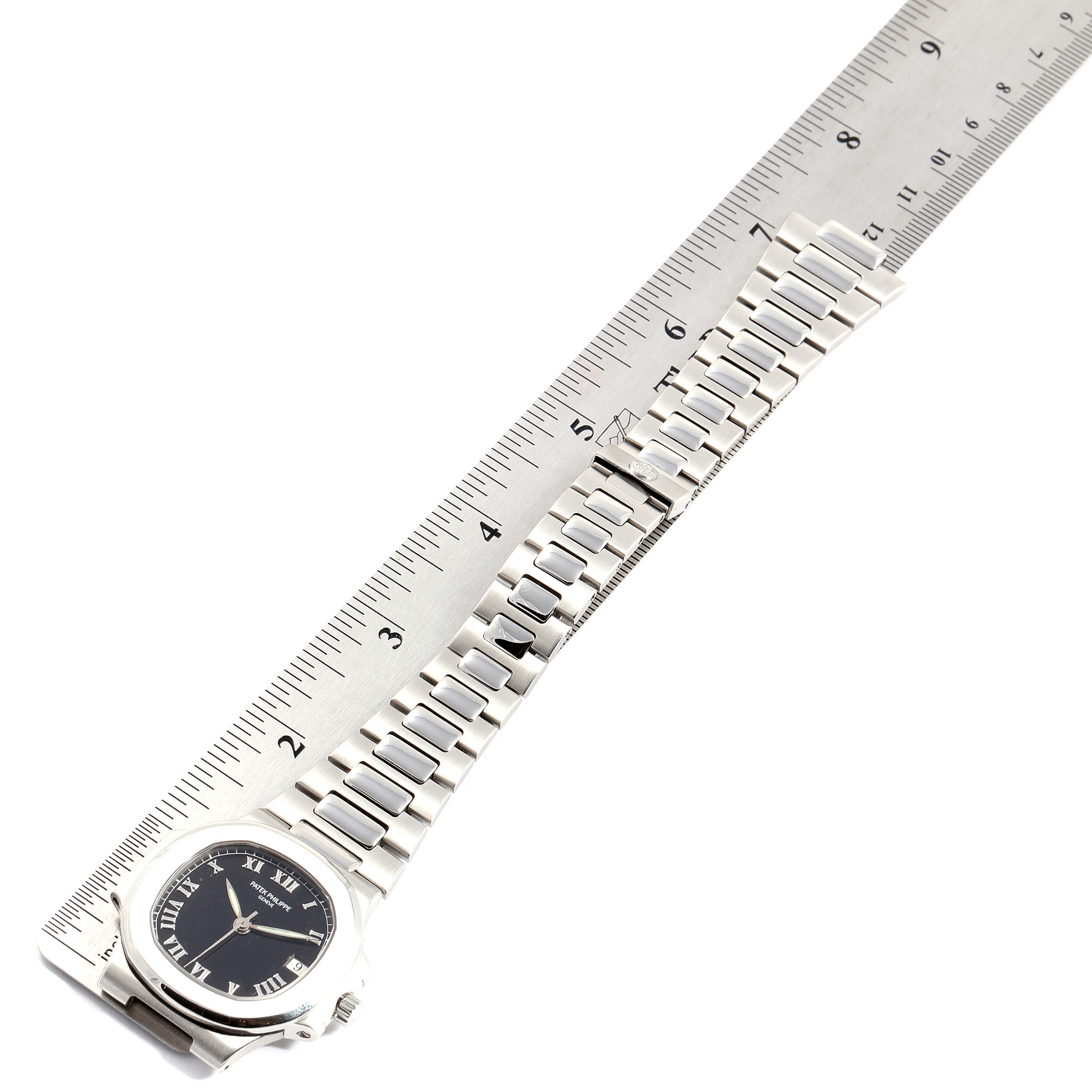 The image shows a Patek Philippe Nautilus 3800/1 Men's Stainless Steel Black Dial 3800/1 Men's Stainless Steel Black Dial watch laid flat along a ruler, displaying its face and bracelet at an overhead angle.