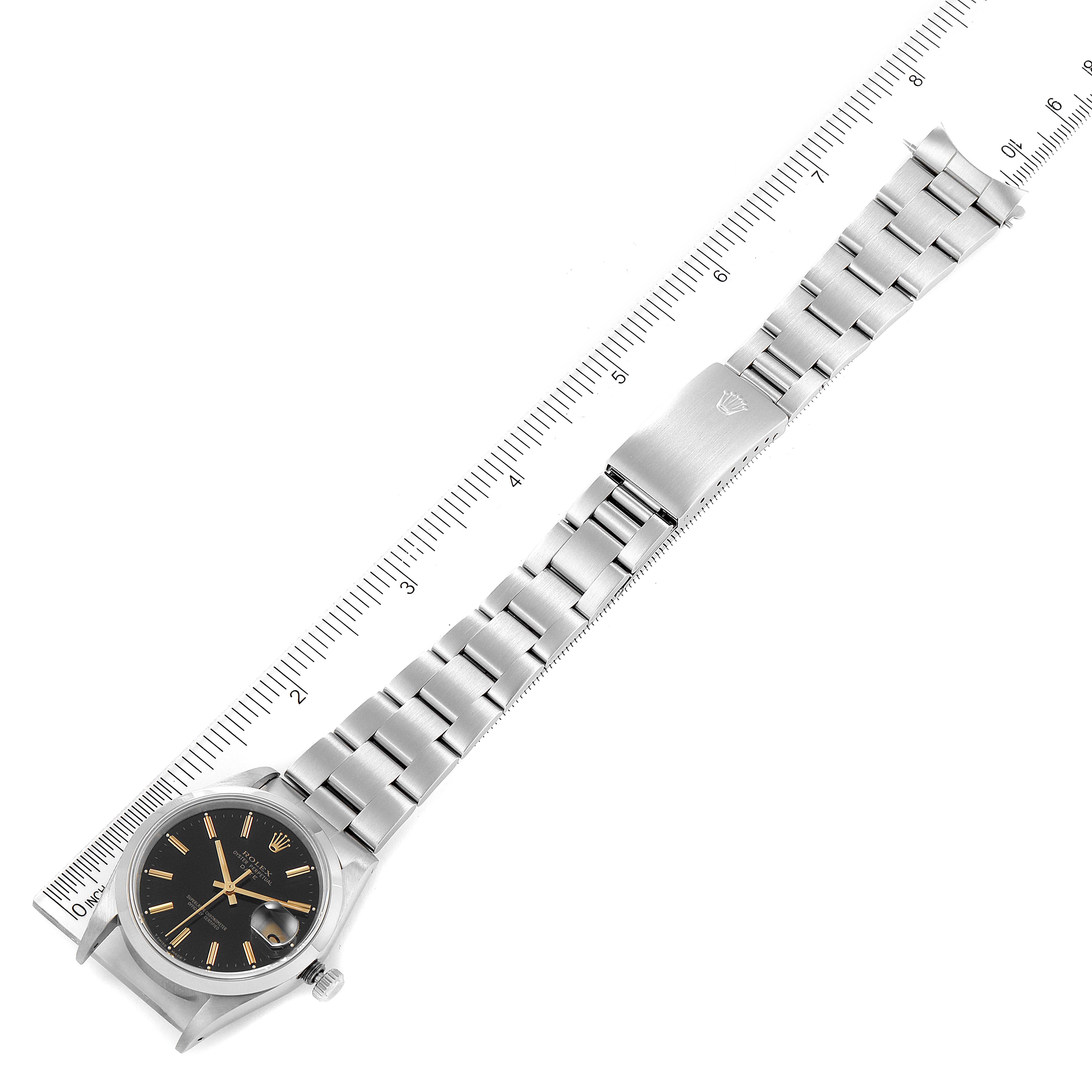 The image shows a Rolex Date 15200 Men's Stainless Steel Black Dial 15200 Men's Stainless Steel Black Dial model watch laid flat next to a ruler, displaying the face and bracelet in a top-down view.