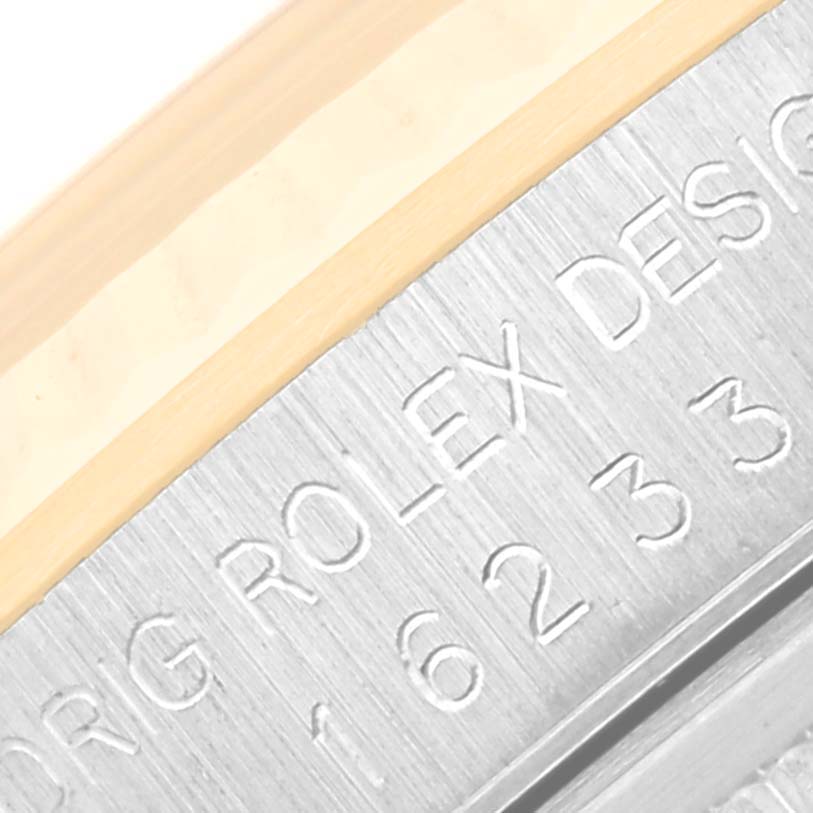 The image shows the side of a Rolex Datejust 16233 Men's Steel and Gold (two tone) Champagne Dial 16233 Men's Steel and Gold (two tone) Champagne Dial watch with engraved text and part of the bezel.