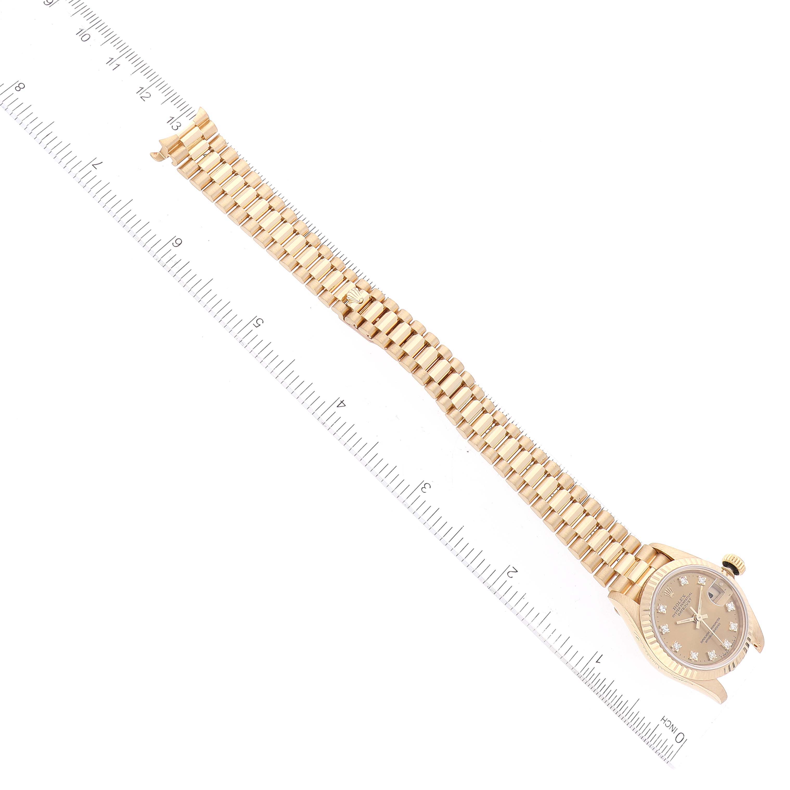 The Rolex President 69178 Women's Yellow Gold Champagne Dial 69178 Women's Yellow Gold Champagne Dial watch is shown from a top-down angle, displaying its entire bracelet and face next to a ruler for measurement.