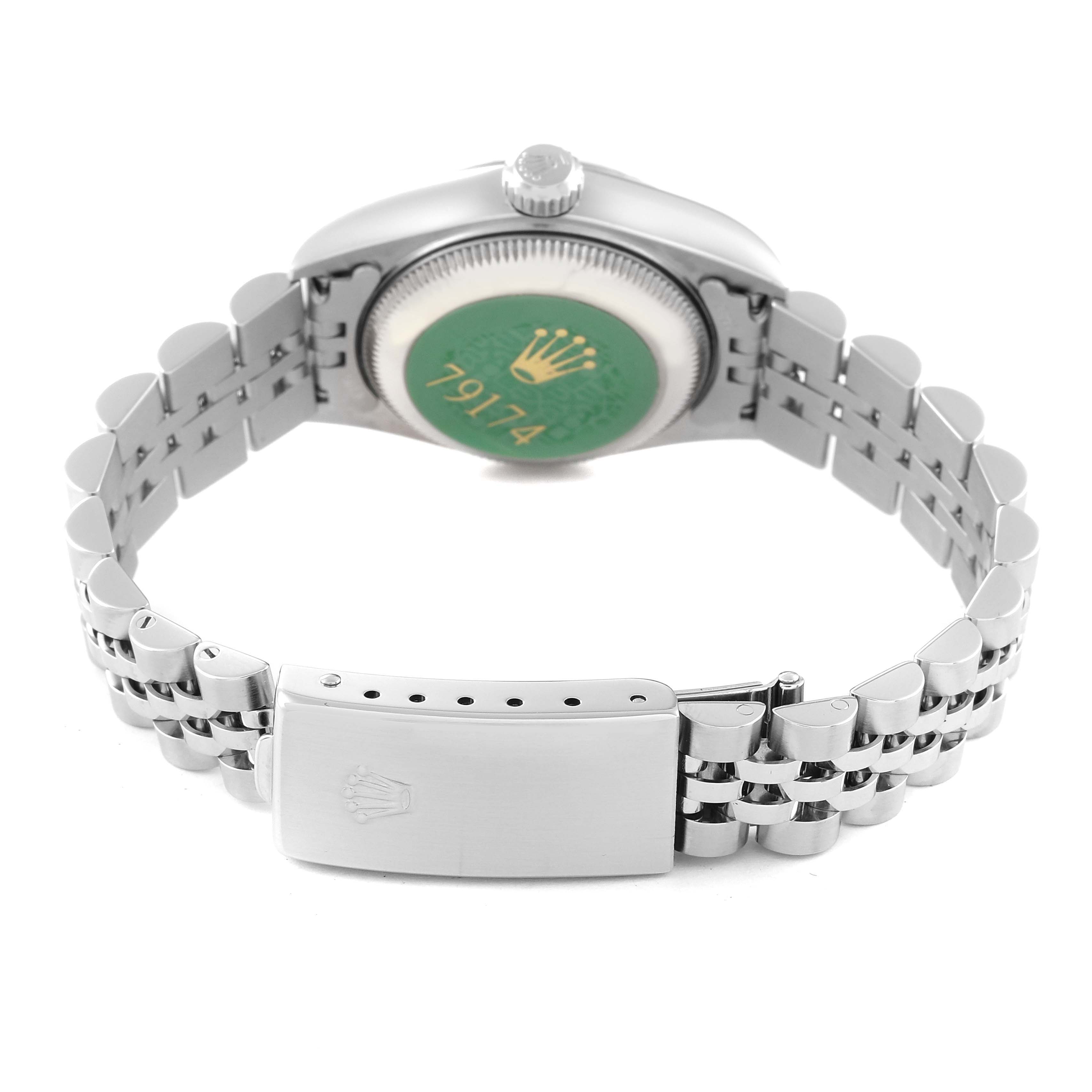 The image shows the back of the Rolex Datejust 79174 Women's Stainless Steel Pink Dial 79174 Women's Stainless Steel Pink Dial watch, focusing on the bracelet and clasp, with the case back featuring a green sticker.