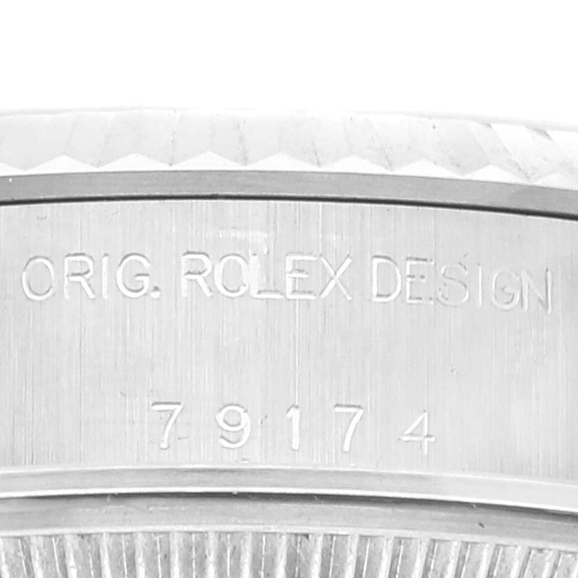 The image shows a close-up of the side of the bezel and case of a Rolex Datejust 79174 Women's Stainless Steel Pink Dial 79174 Women's Stainless Steel Pink Dial watch, featuring engraved text.
