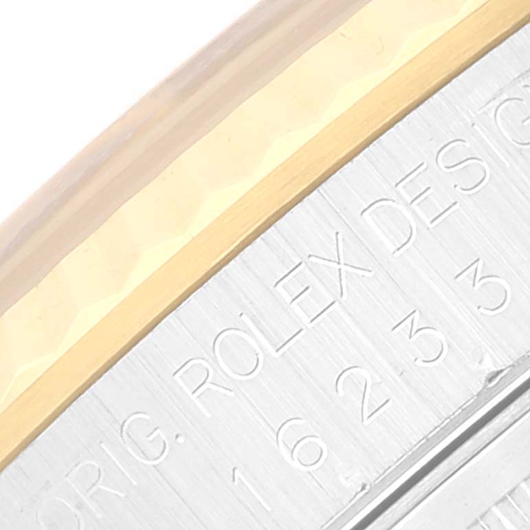 The image shows a close-up of the side engraving "ORIG. ROLEX DESIGN" on a Rolex Datejust 16233 Men's Steel and Gold (two tone) Blue Dial 16233 Men's Steel and Gold (two tone) Blue Dial watch bezel.