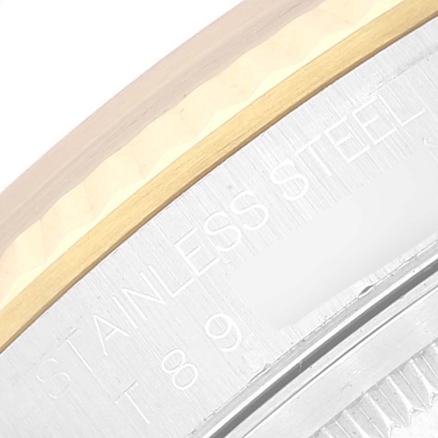 The image shows a close-up of the edge of a Rolex Datejust 16233 Men's Steel and Gold (two tone) Blue Dial 16233 Men's Steel and Gold (two tone) Blue Dial watch, focusing on the stainless steel and gold bezel, with part of the engraved text visible.