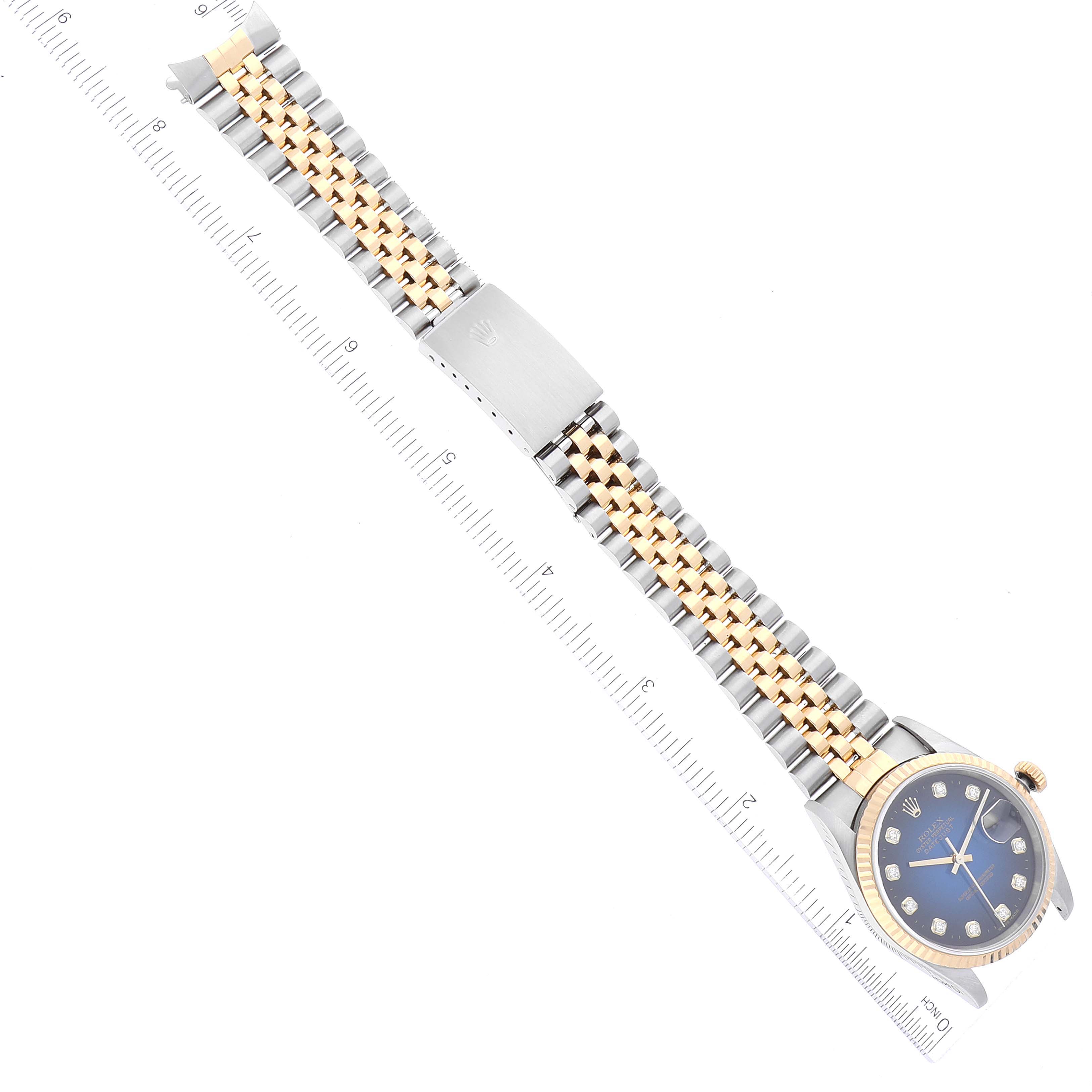The image shows the Rolex Datejust 16233 Men's Steel and Gold (two tone) Blue Dial 16233 Men's Steel and Gold (two tone) Blue Dial watch laying flat, displaying the face, bracelet, and clasp next to a ruler for size reference.