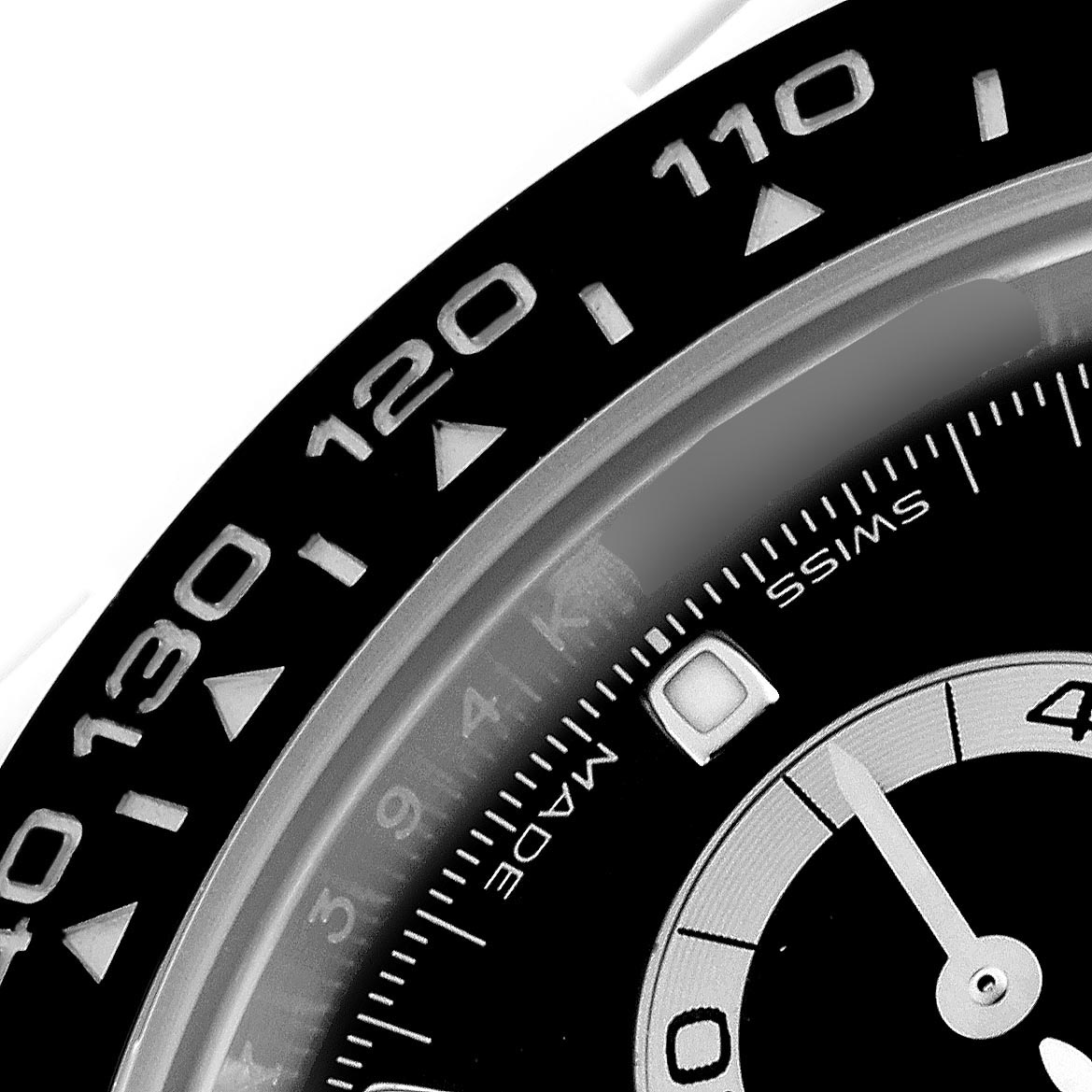 The image shows a close-up of the bezel and part of the dial of a Rolex Daytona 116500 Men's Stainless Steel Black Dial 116500 Men's Stainless Steel Black Dial watch.