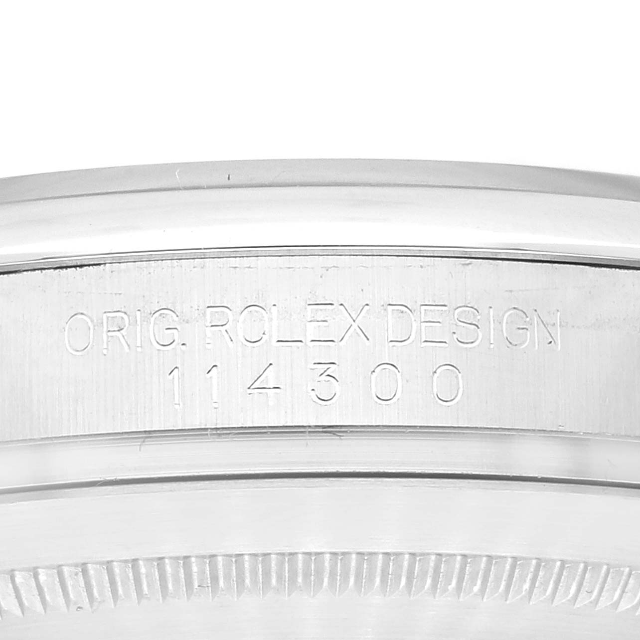 The image shows a close-up of the engraved side of the case of a Rolex Oyster Perpetual 114300 Men's Stainless Steel Grey Dial 114300 Men's Stainless Steel Grey Dial model, highlighting the design number 114300.