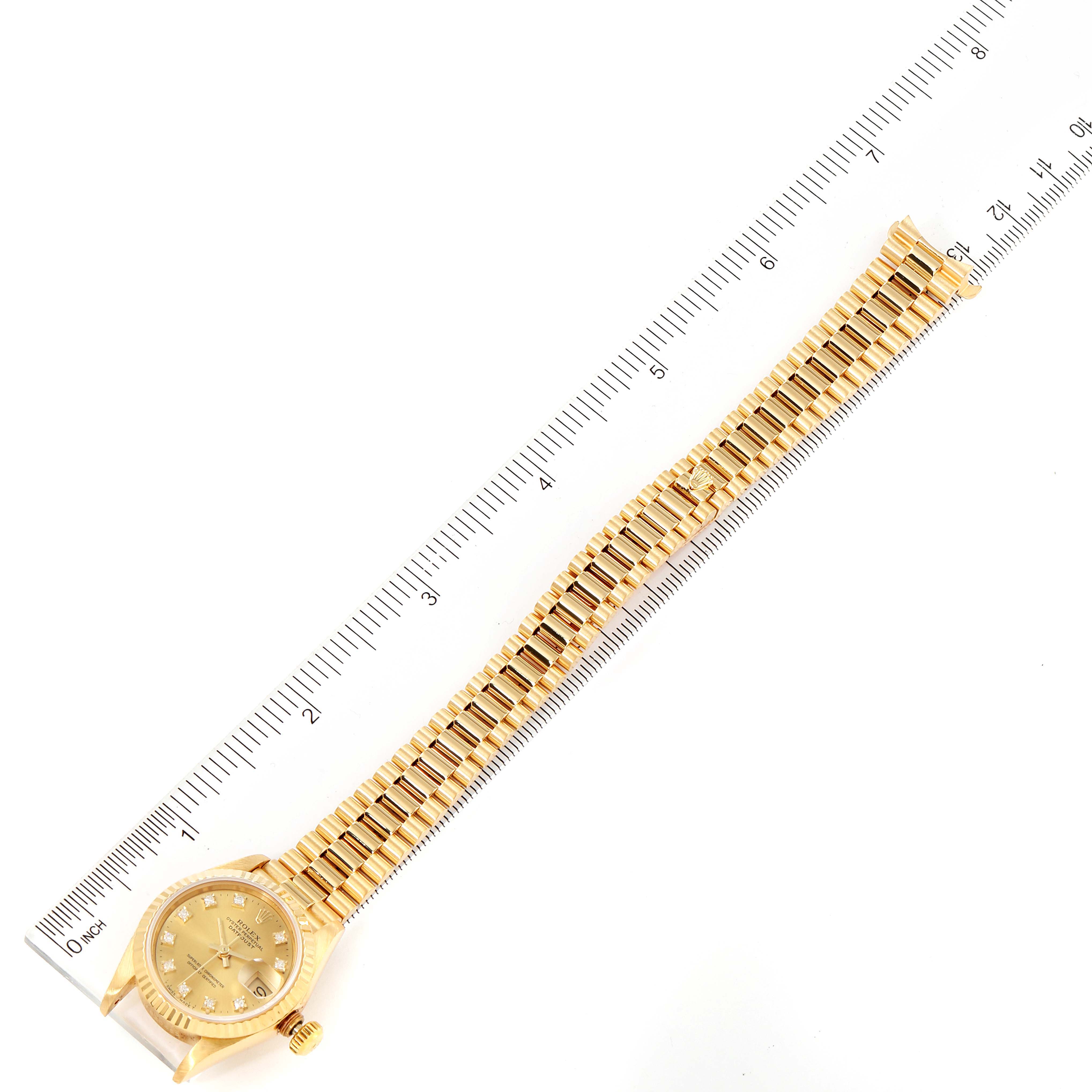 This image shows the Rolex President 69178 Women
s Yellow Gold Champagne Dial 69178 Women
s Yellow Gold Champagne Dial model watch laid flat with a ruler alongside for scale.