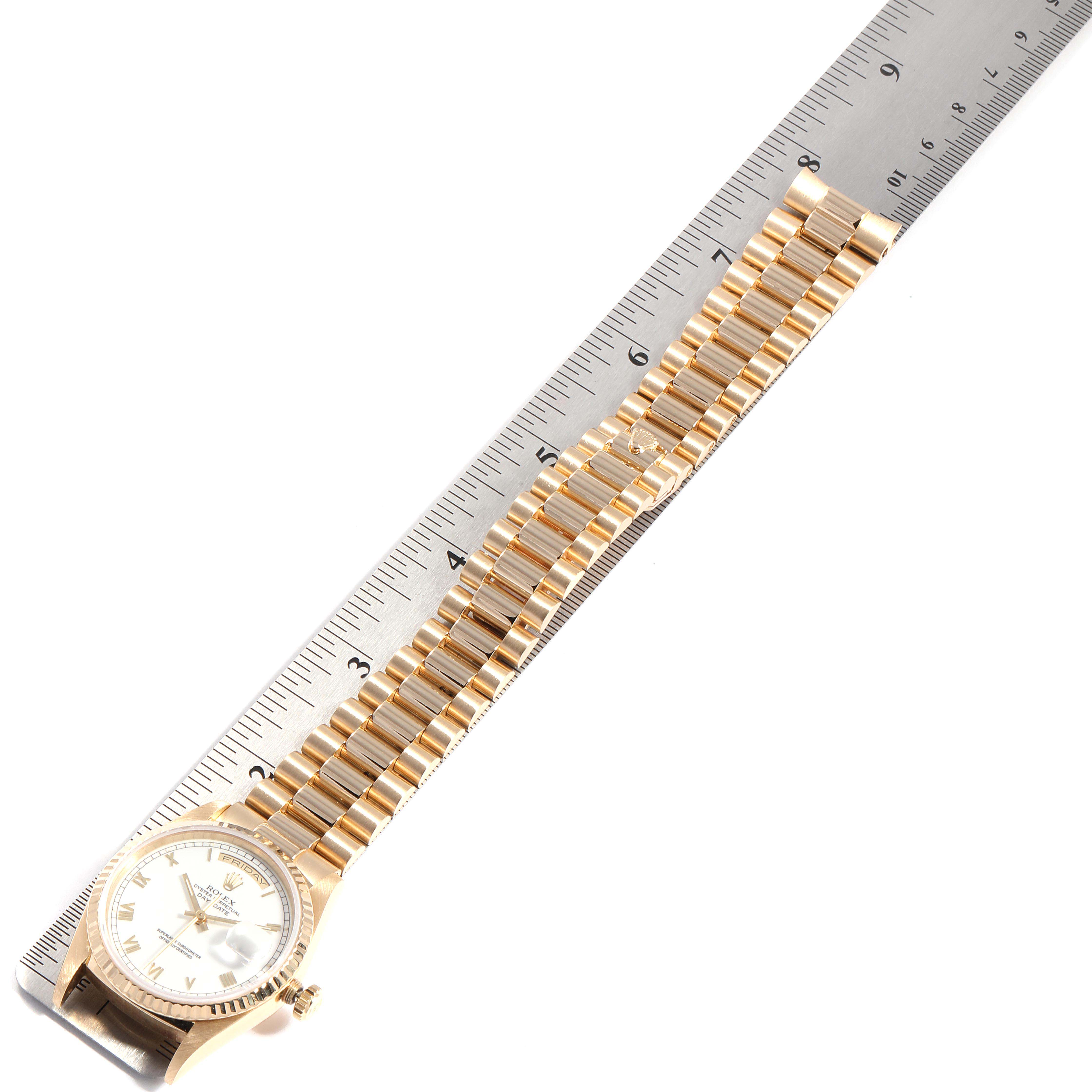 A Rolex President 18238 Men
s Yellow Gold White Dial 18238 Men
s Yellow Gold White Dial model watch is shown laid flat with its gold bracelet measured against a ruler.