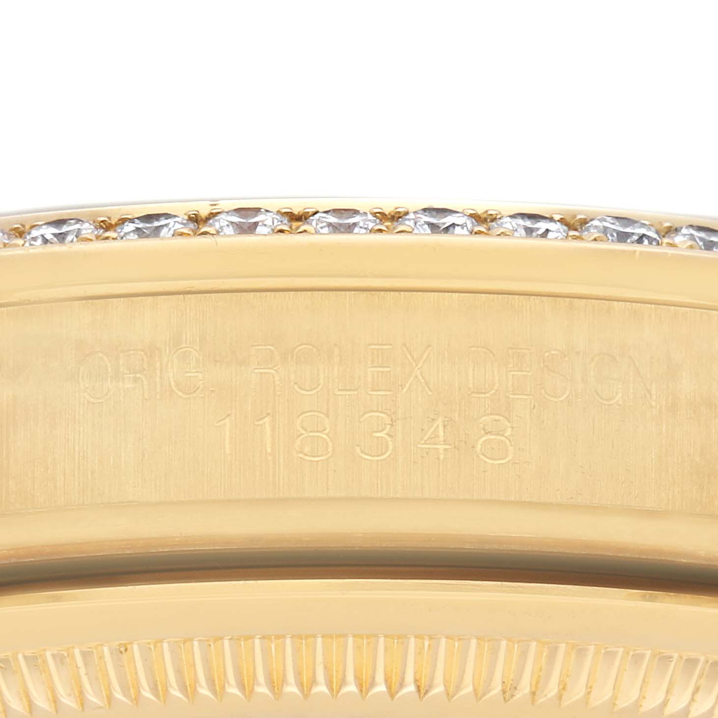 The image shows the engraved side of a Rolex President 118348 Men
s Yellow Gold Champagne Dial 118348 Men
s Yellow Gold Champagne Dial model, focusing on the case
s edge and part of the diamond bezel.