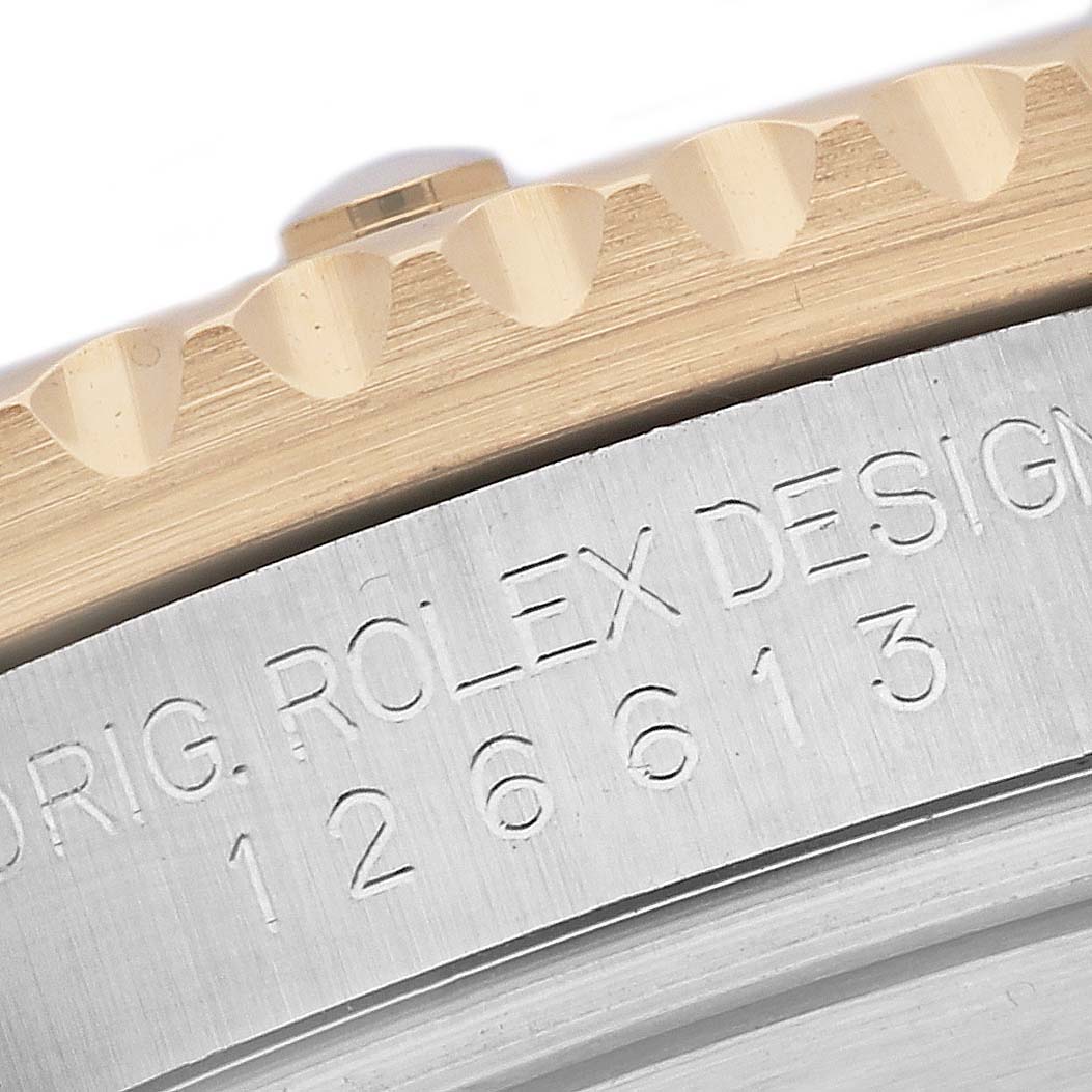 This close-up image of a Rolex Submariner 126613 Men's Steel and Gold (two tone) Blue Dial 126613 Men's Steel and Gold (two tone) Blue Dial shows part of the bezel and the case with engraved text.