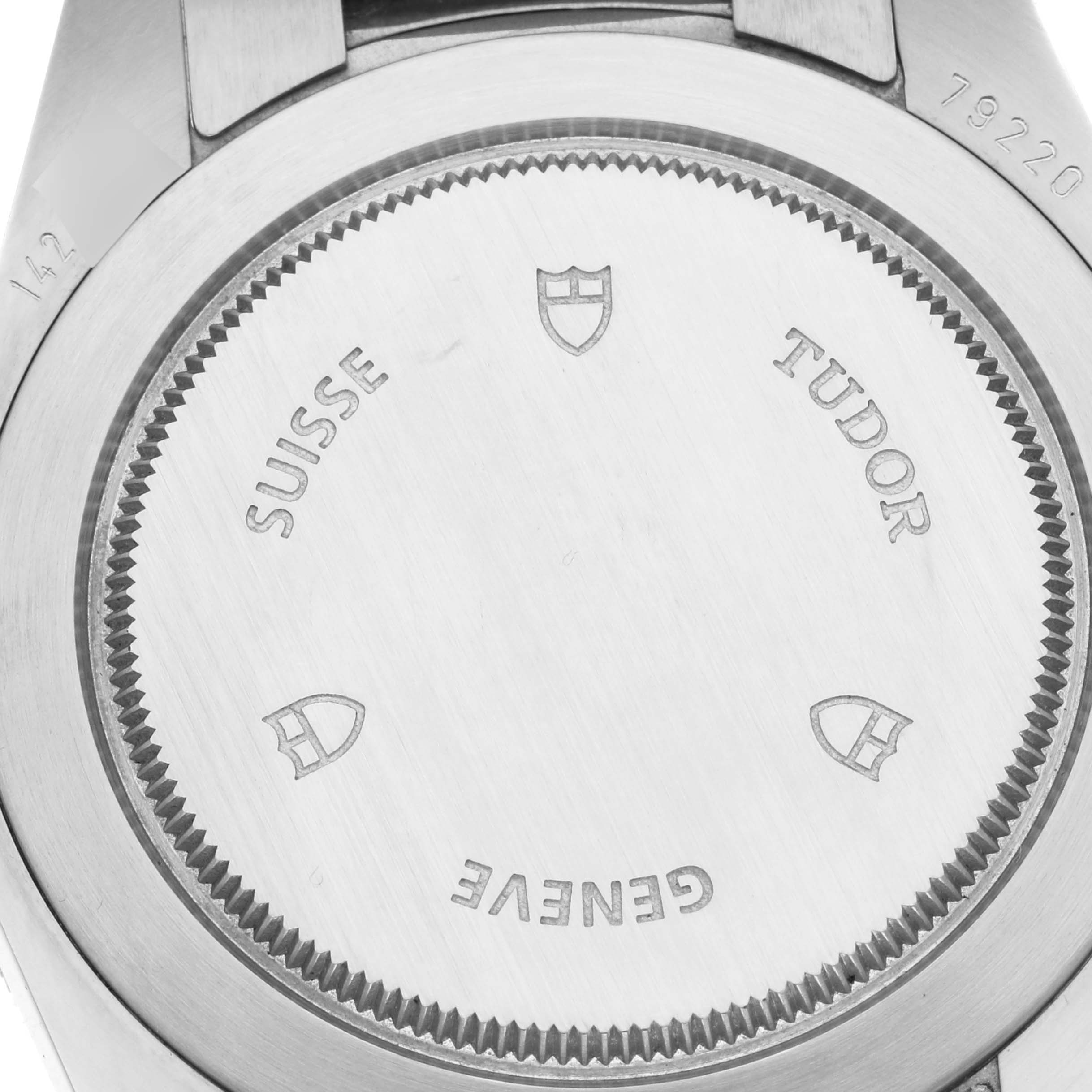 The image shows the back case of a Tudor Heritage Black Bay 79220R Men
s Stainless Steel Black Dial 79220R Men
s Stainless Steel Black Dial watch, displaying the brand name and various engravings.