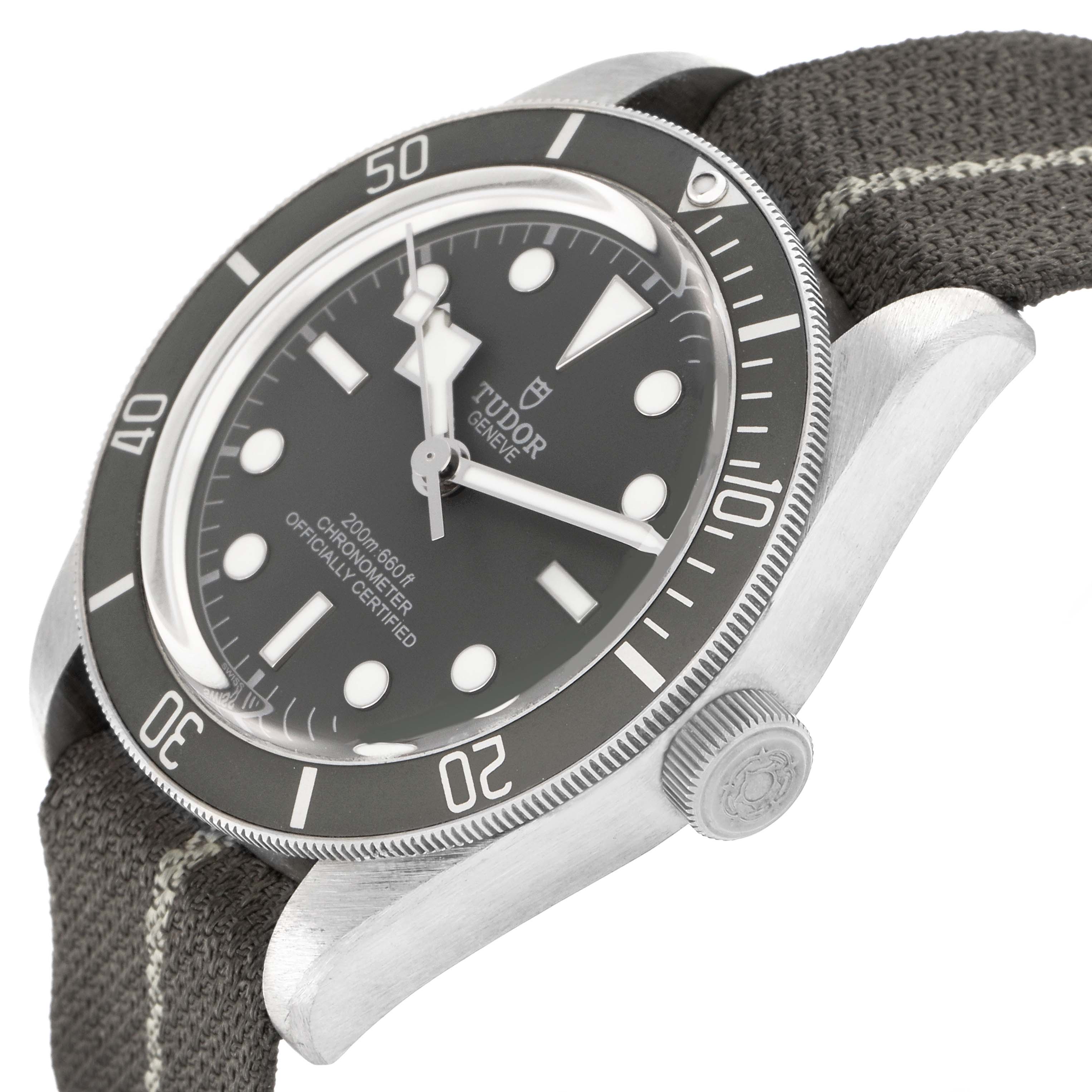 The Tudor Heritage Black Bay 79010 Men
s Stainless Steel Grey Dial 79010 Men
s Stainless Steel Grey Dial watch is shown at an angled side view, highlighting the bezel, crown, and fabric strap.
