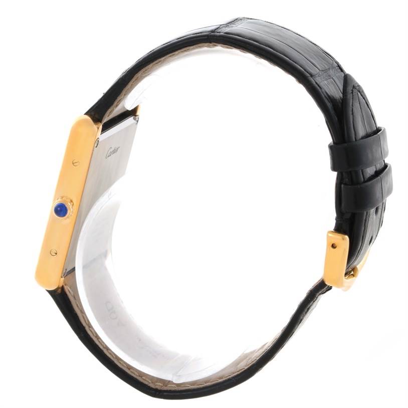 The image shows a Cartier Tank Solo W1018855 Men
s Steel and Gold (two tone) Silver Dial W1018855 Men
s Steel and Gold (two tone) Silver Dial watch from a side angle, featuring its black leather strap and gold case with a blue cabochon crown.