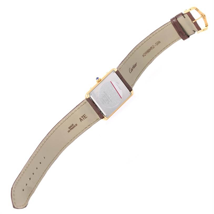 The image shows the back side of the Cartier Tank Solo W1018855 Men
s Steel and Gold (two tone) Silver Dial W1018855 Men
s Steel and Gold (two tone) Silver Dial watch, including its case back, crown, and leather strap with branding and serial numbers.