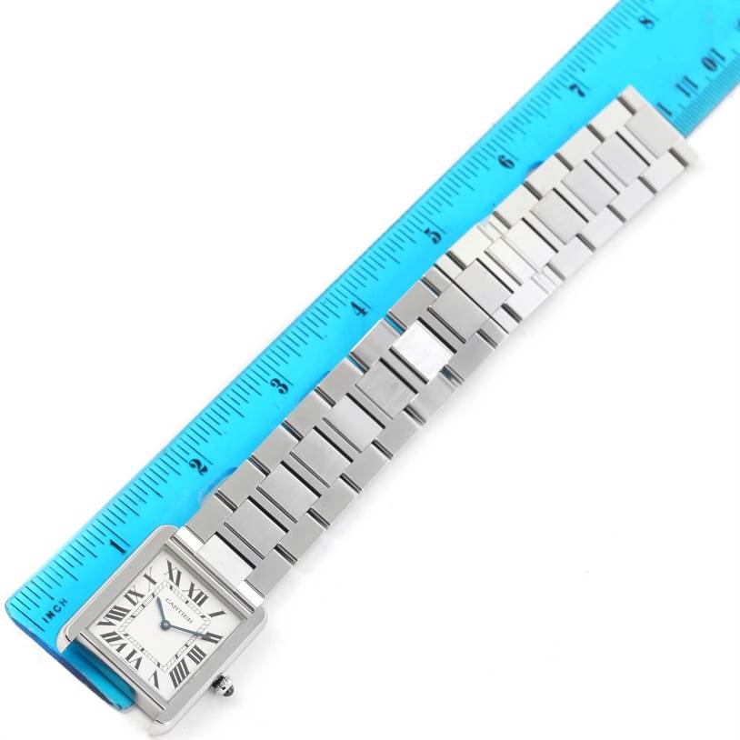 The Cartier Tank Solo W5200014 Men
s Stainless Steel Silver Dial W5200014 Men
s Stainless Steel Silver Dial watch is shown flat with its face and metal bracelet laying next to a blue ruler for measurement.