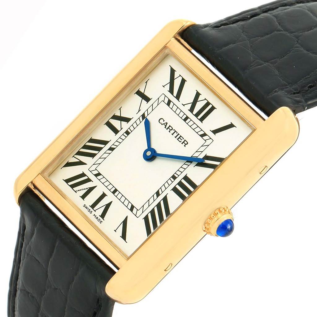 The image shows the face and part of the strap of the Cartier Tank Solo W1018855 Men
s Steel and Gold (two tone) Silver Dial W1018855 Men
s Steel and Gold (two tone) Silver Dial watch, including its crown with a blue cabochon.