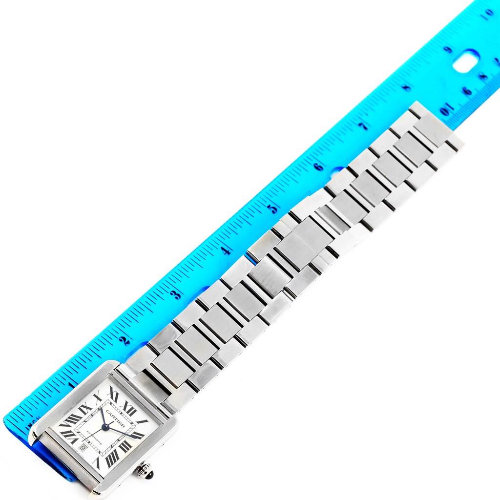 The Cartier Tank Solo W5200028 Men
s Stainless Steel Silver Dial W5200028 Men
s Stainless Steel Silver Dial watch is shown from an overhead angle with its face and metal bracelet beside a blue ruler.