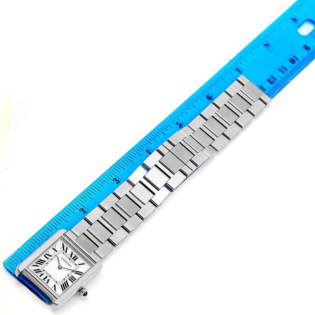 The Cartier Tank Solo W5200014 Men
s Stainless Steel Silver Dial W5200014 Men
s Stainless Steel Silver Dial watch is shown from an angled top view, including its face and metal bracelet alongside a blue ruler.