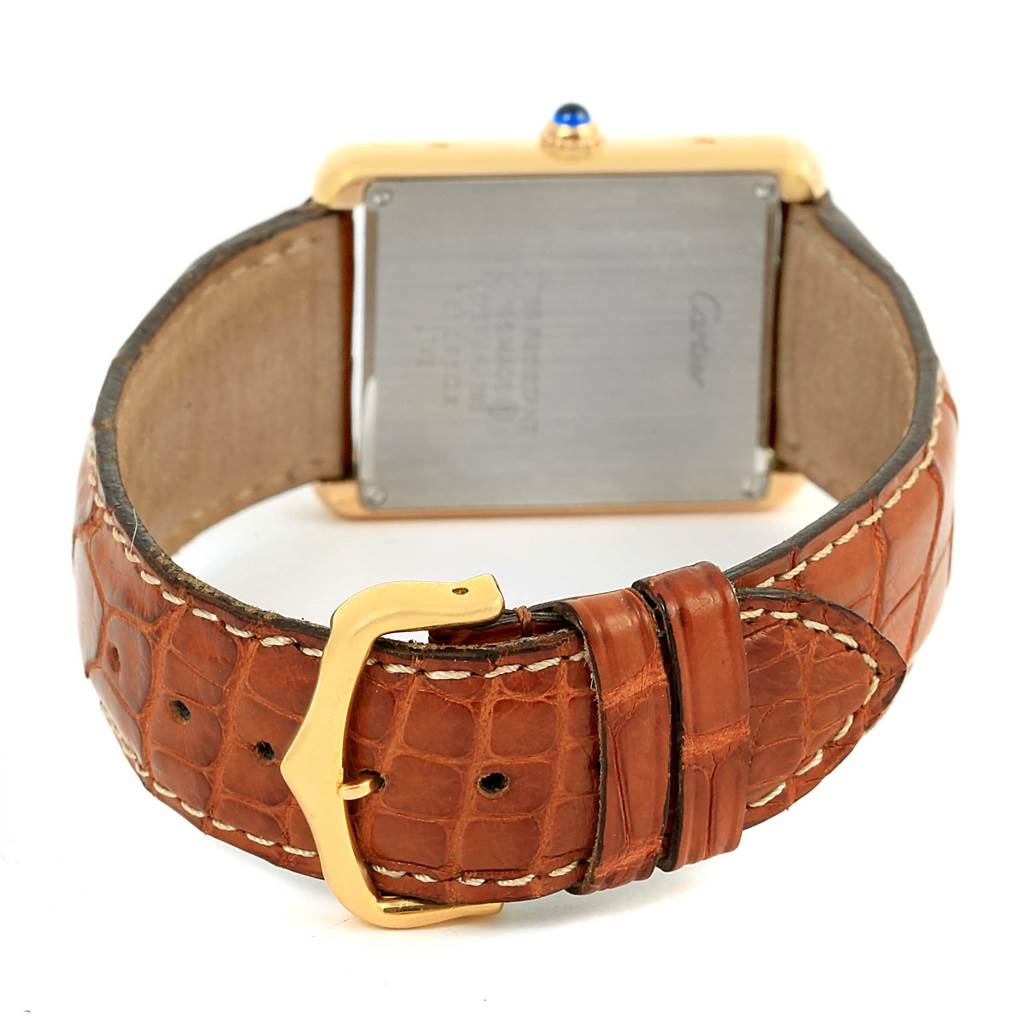 The image shows the back of a Cartier Tank Solo W1018855 Men
s Steel and Gold (two tone) Silver Dial W1018855 Men
s Steel and Gold (two tone) Silver Dial watch and its brown leather strap with a gold buckle.