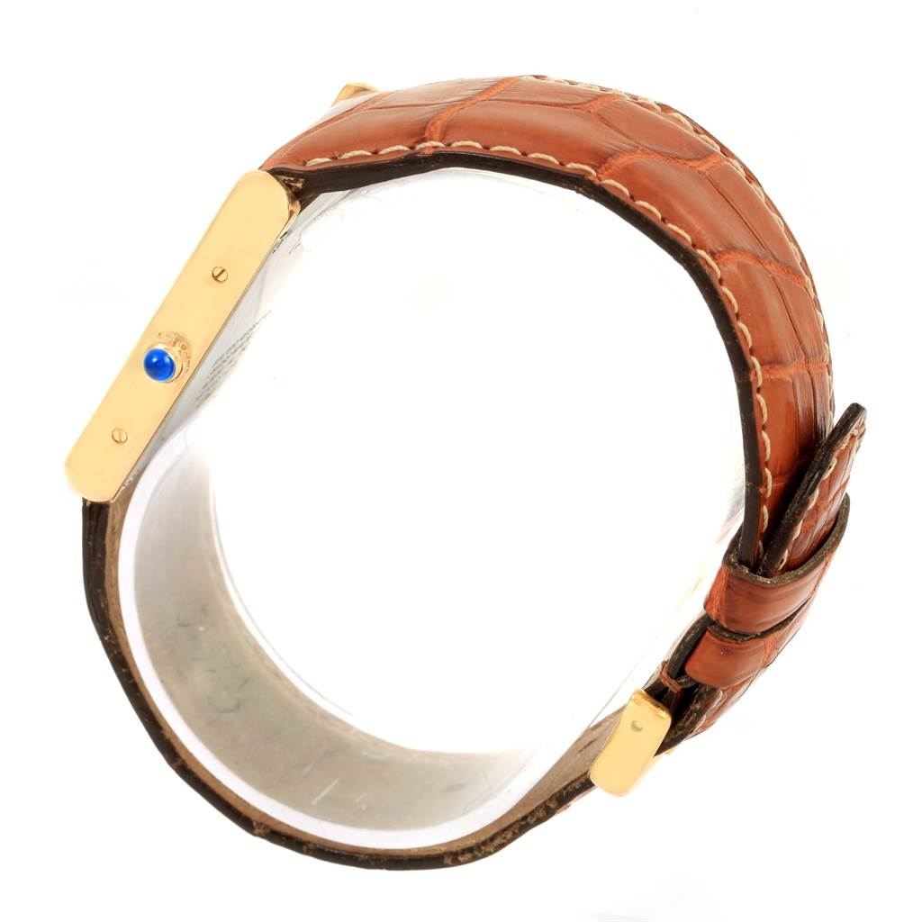 The image shows a side view of a Cartier Tank Solo W1018855 Men
s Steel and Gold (two tone) Silver Dial W1018855 Men
s Steel and Gold (two tone) Silver Dial watch highlighting its brown leather strap and gold casing with a blue cabochon crown.